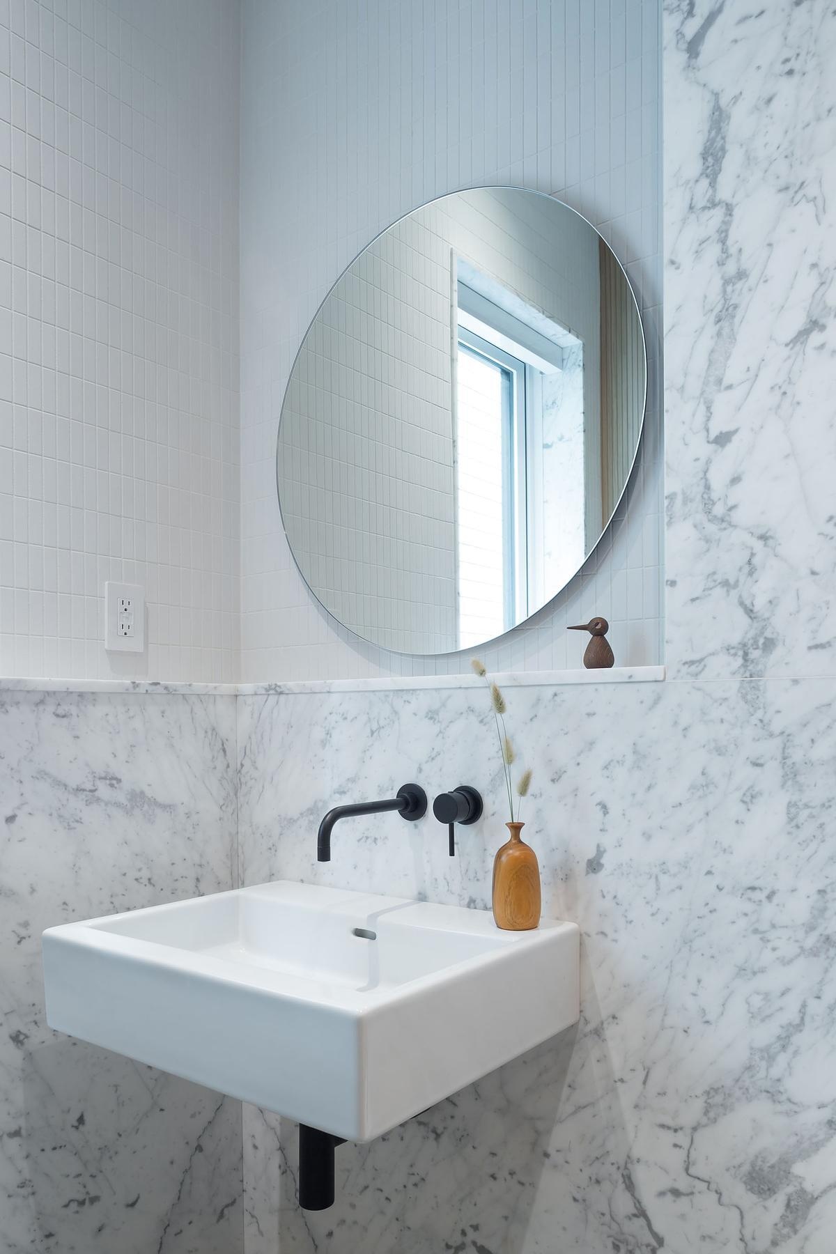 Clad in marble, this small powder room makes a big impact with bold veining and a minimal palette. Perfectly tied to the home's overall design.