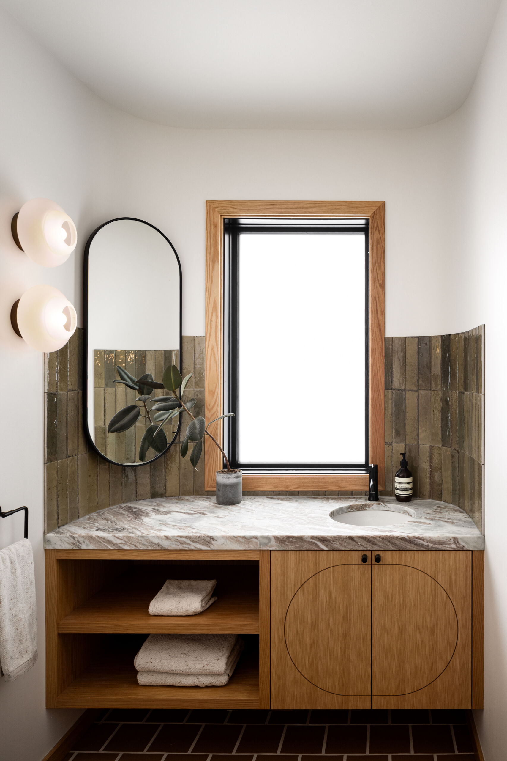 Small but impactful, the powder room is a perfect example of the home’s “curves and whimsy” philosophy. Instead of fighting against a window, the team leaned into the challenge by offsetting the vanity mirror, creating a Zen-like, asymmetric balance. It’s a reminder that good design doesn’t always mean symmetry, but harmony.