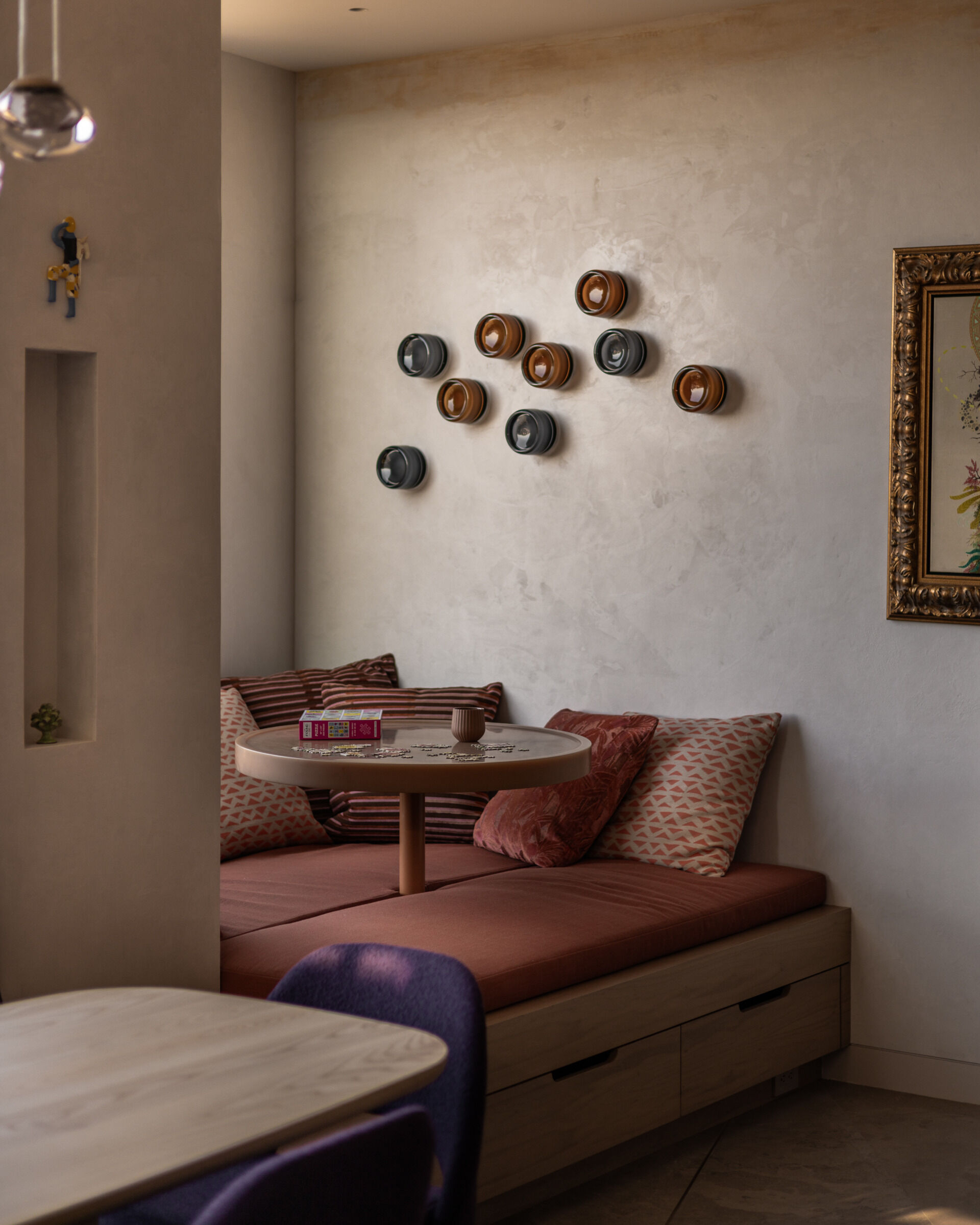 Just past the dining area, a custom bay window nook brings a playful architectural moment. The built-in seating is paired with a resin-topped, rotating game table that invites spontaneous board games or lazy weekend lounging.