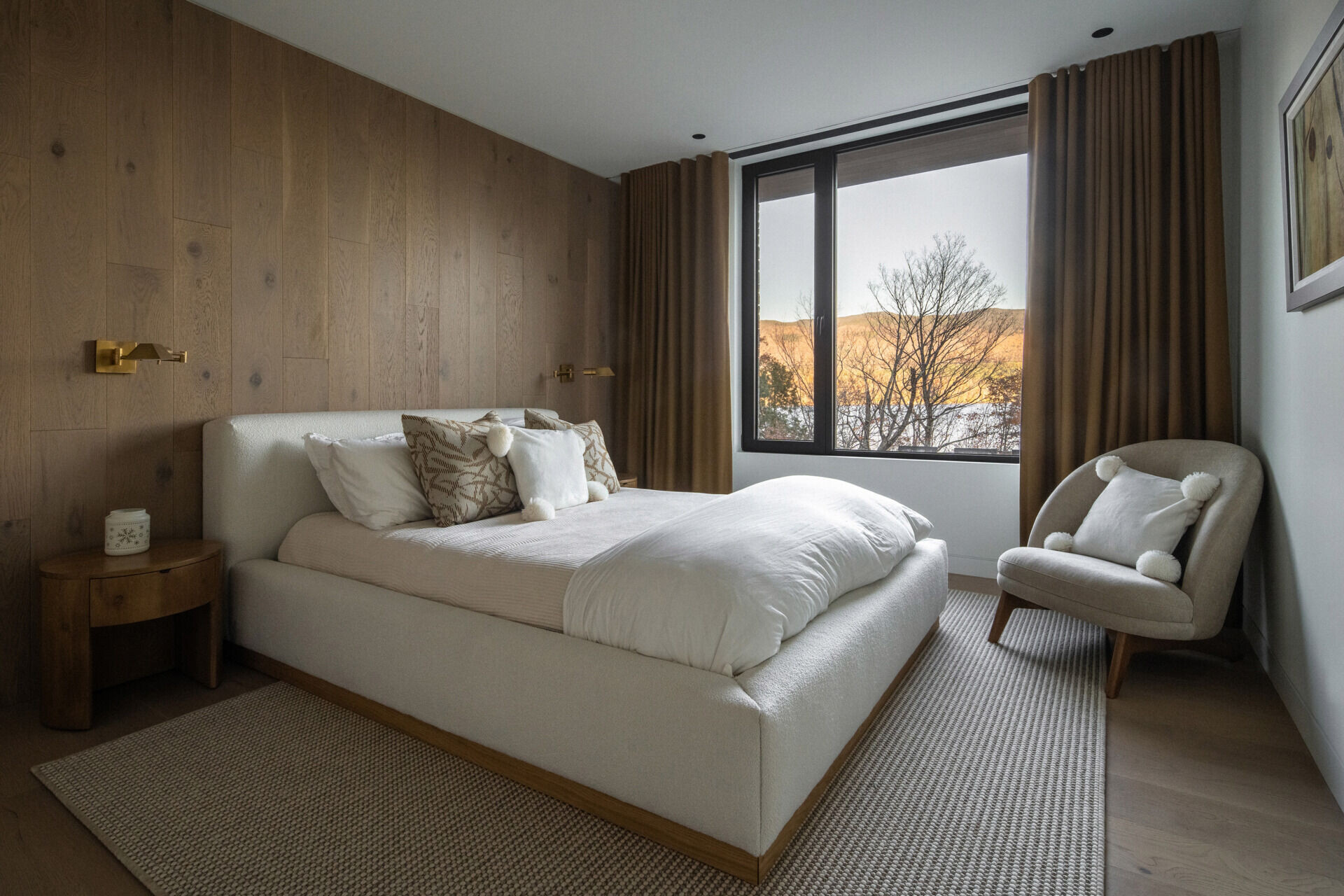 A guest bedroom with a warm, natural aesthetic, with a wall of wide-plank wood paneling adding texture and warmth to the space.