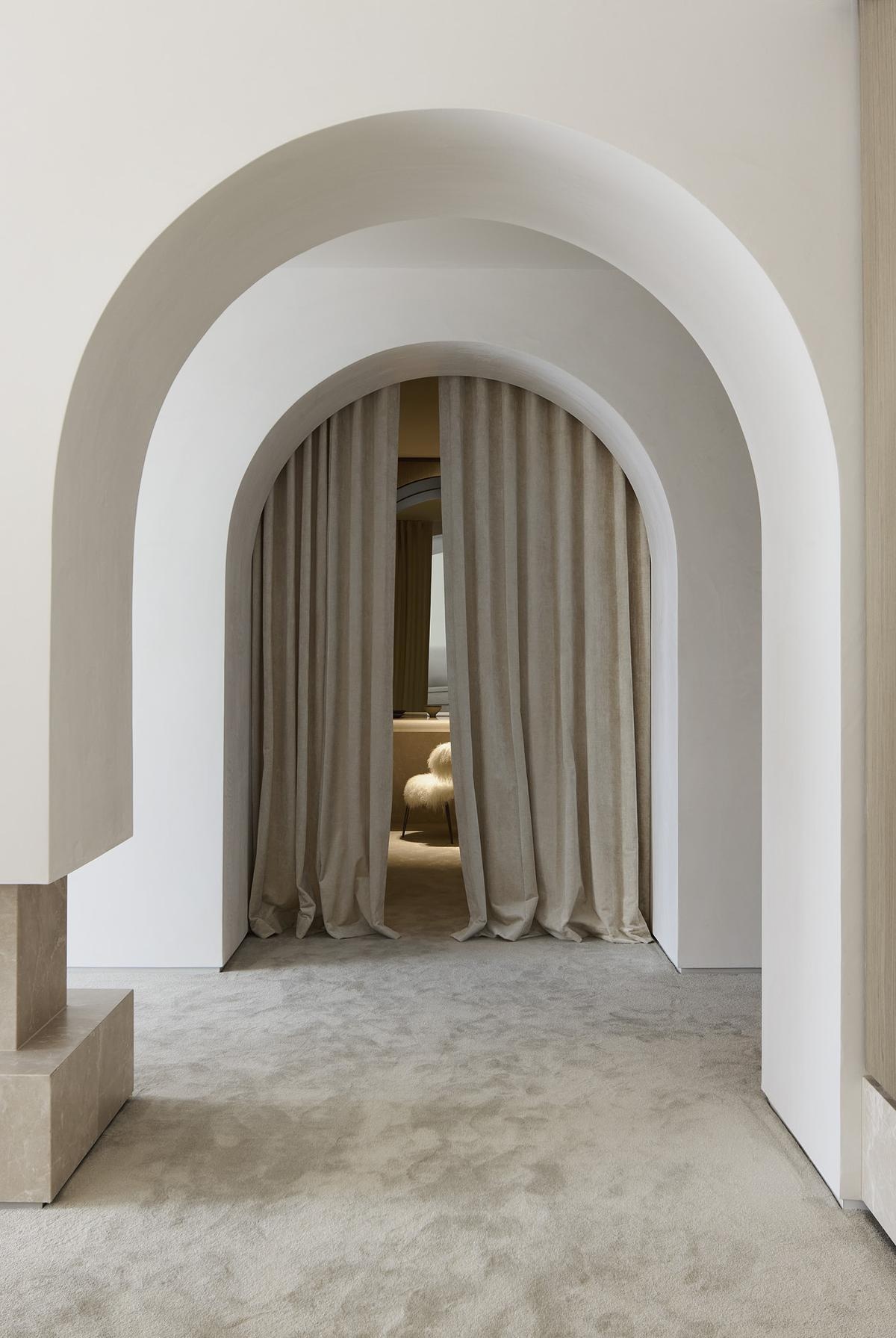 The primary suite evokes soft escape, with sandy tones, travertine finishes, and iconic furnishings like the Eames Lounge Chair. A fireplace and walk-in robe complete the space, offering both connection and privacy.