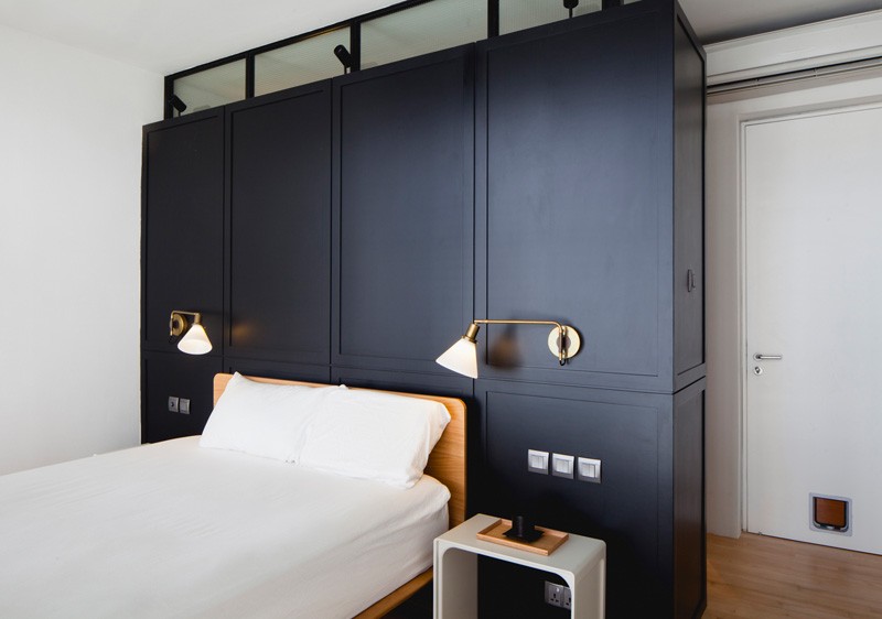 The Black Box accent wall introduces a wardrobe that doubles as a headboard, bringing structure and depth to the minimalist bedroom.
