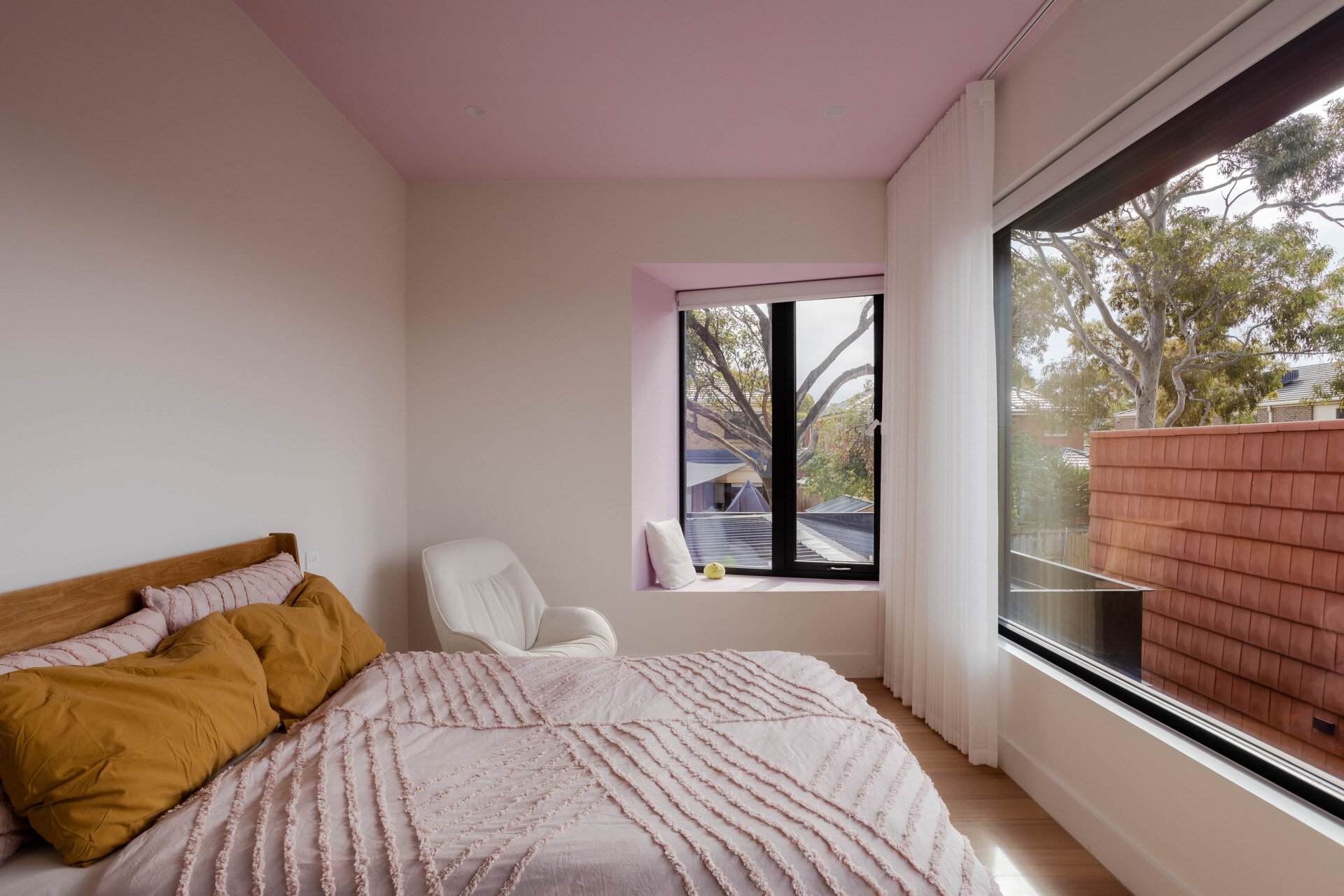 This girls’ bedroom is light-filled and cheerful, with a light Lavender Rose painted ceiling and angled window seat.