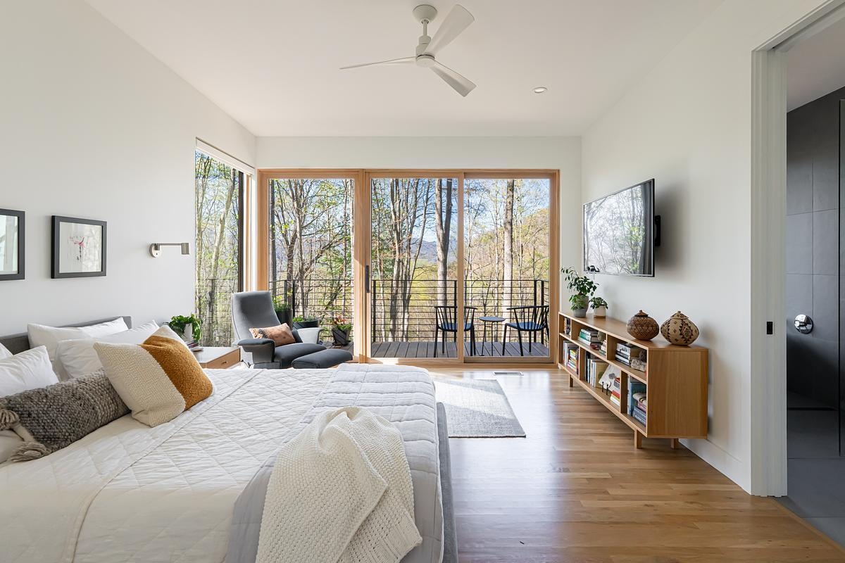 A primary bedroom, designed as a private sanctuary with its own quiet deck that looks out onto the landscape.