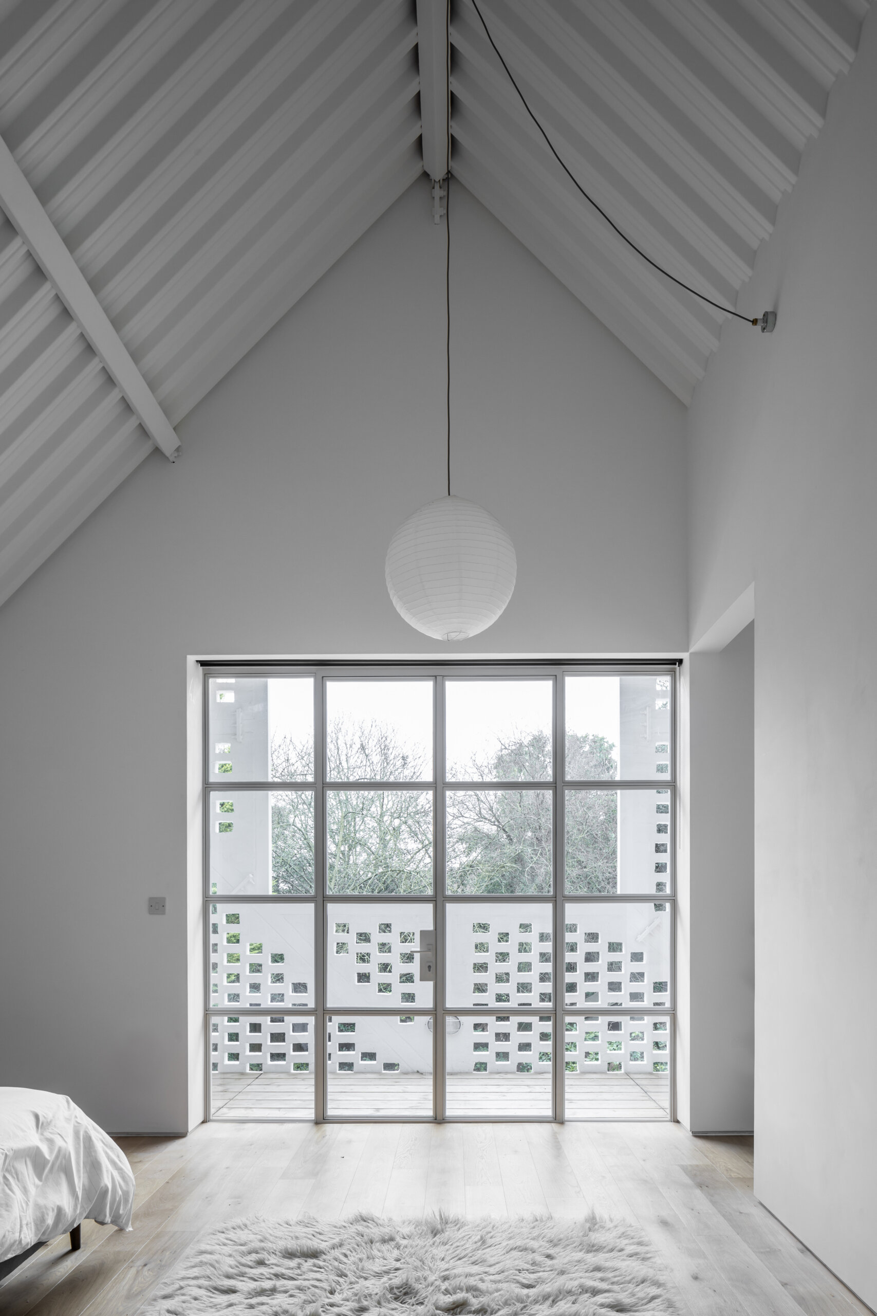 Set under a soaring five-meter roof, the bedroom is peaceful and light-filled, a calm retreat tucked into the top of the house.