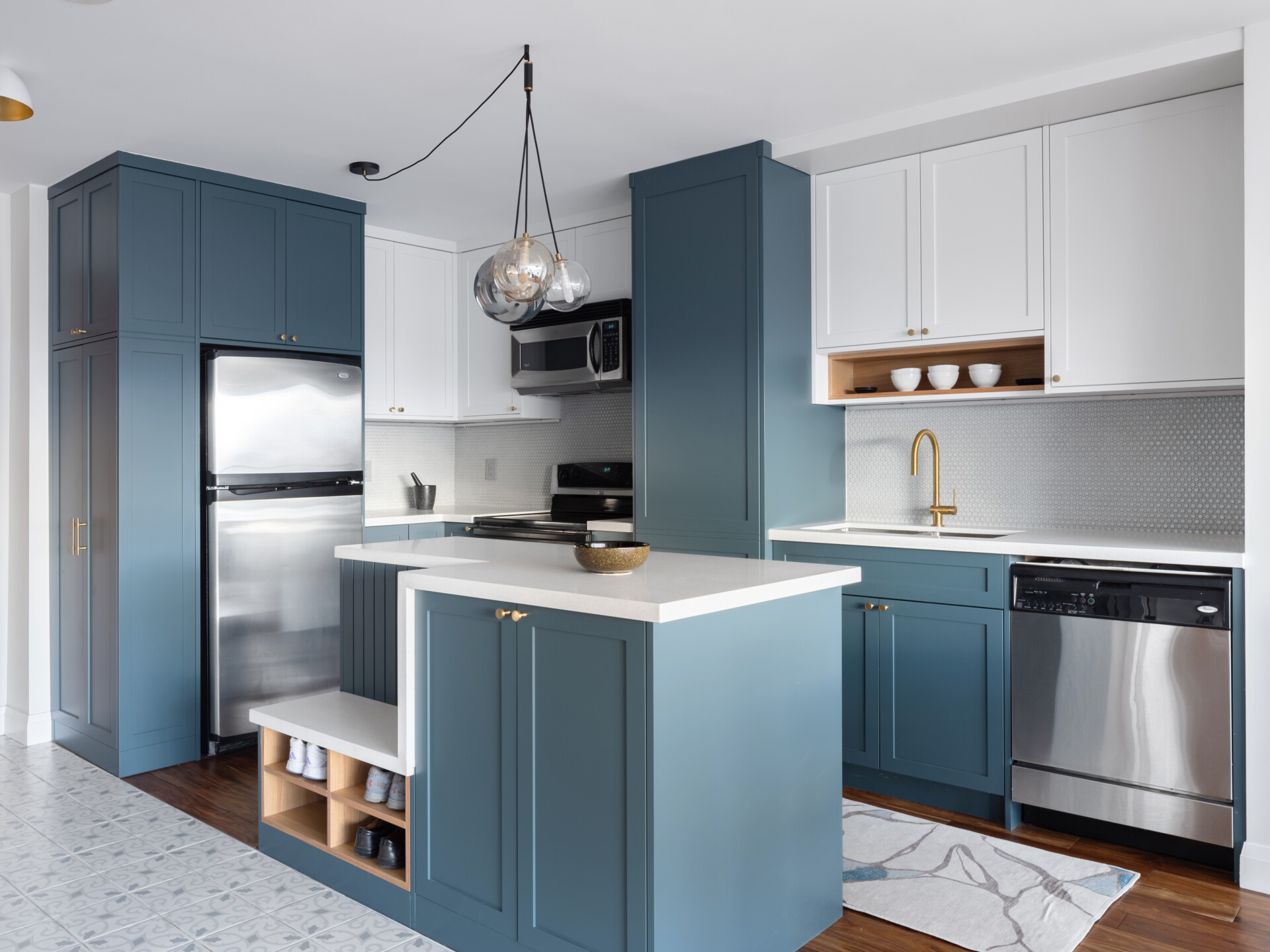 A reoriented kitchen with a blue and white color palette, has a dual-purpose island bringing storage, seating, and flow to the heart of this apartment.