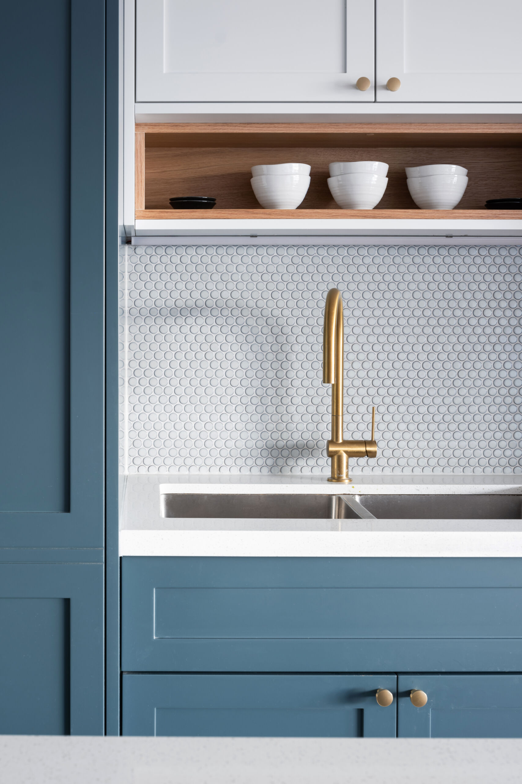 A reoriented kitchen with a blue and white color palette, has a dual-purpose island bringing storage, seating, and flow to the heart of this apartment.