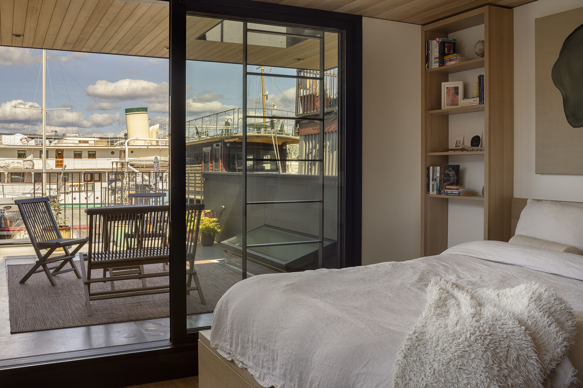 Upstairs in the floathome, custom cabinetry integrates the bed, closet, and shelves, opening onto a roof deck for expanded living.
