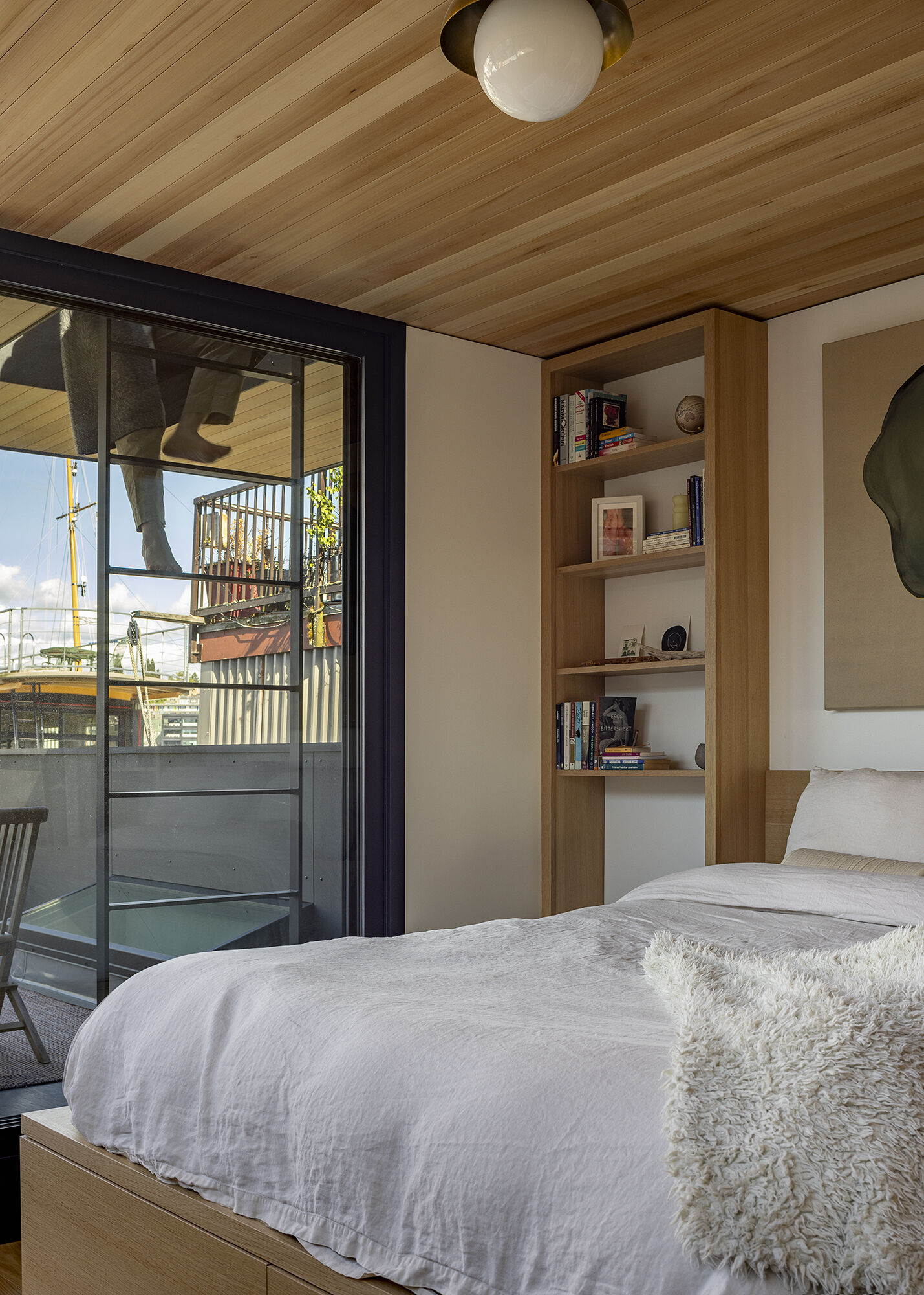 Upstairs in the floathome, custom cabinetry integrates the bed, closet, and shelves, opening onto a roof deck for expanded living.