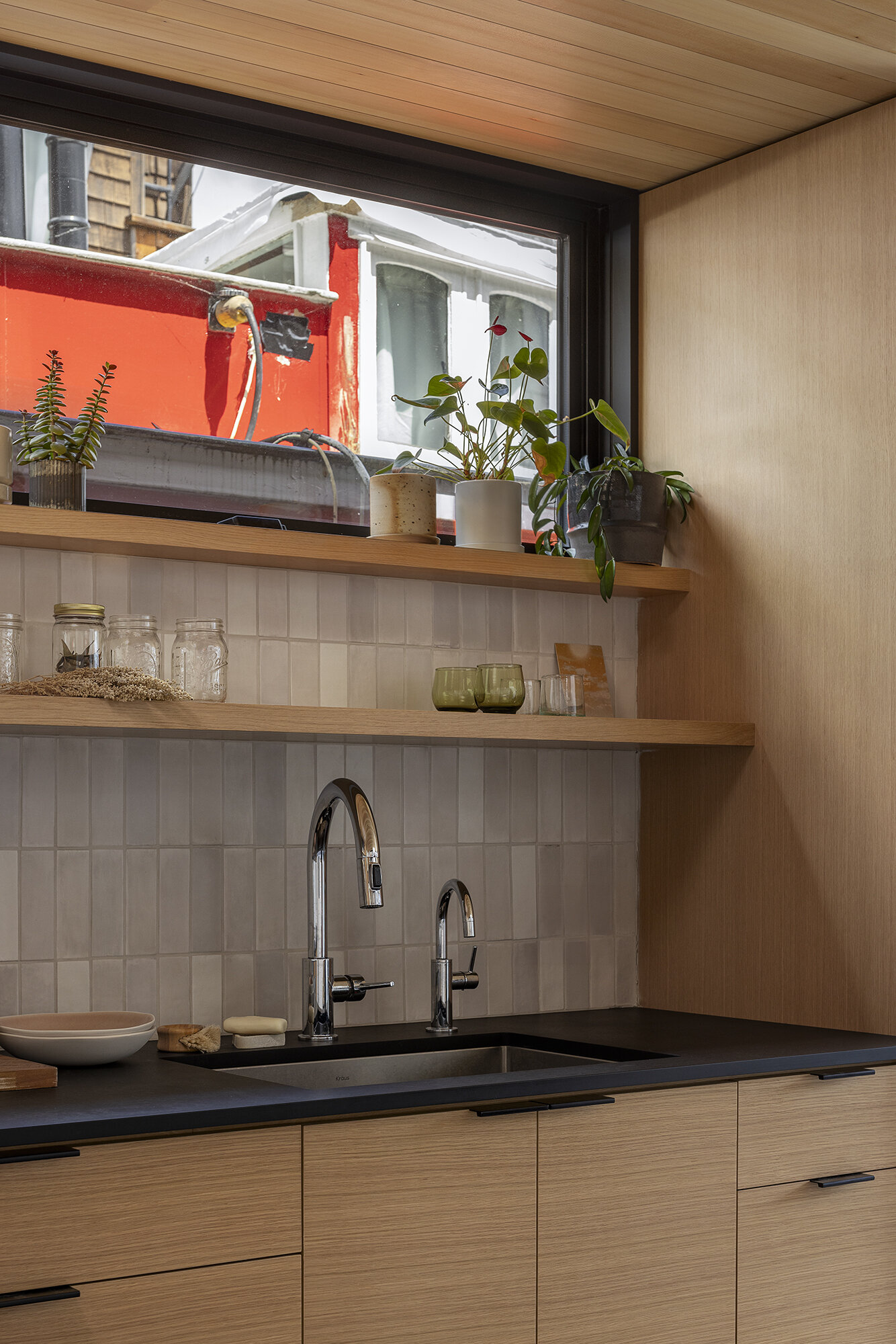 Inside the floathome, an L-shaped kitchen with custom oak cabinetry and a movable island delivers full-function cooking in a minimal space.