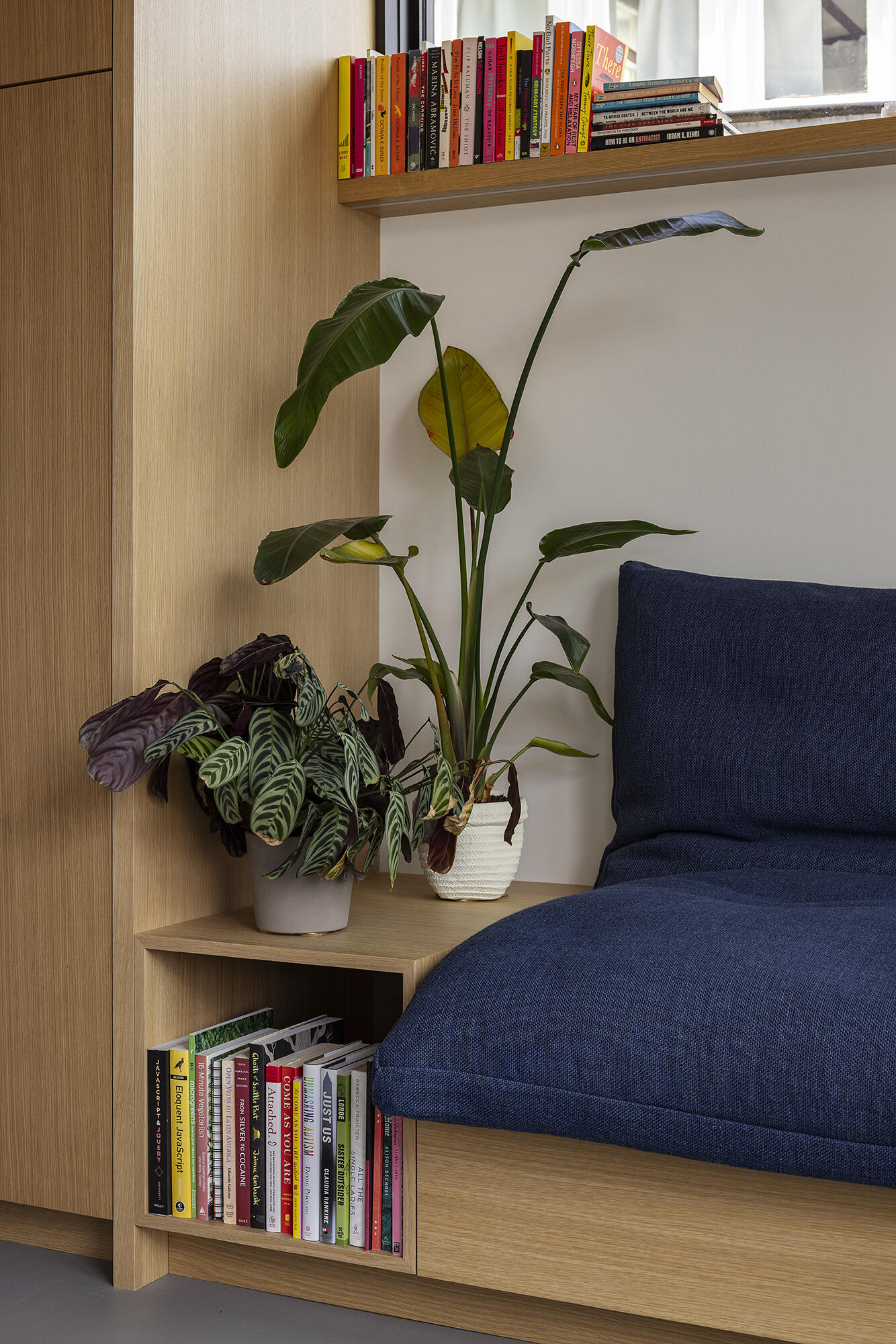 This floathome’s living room features a built-in oak sofa with hidden storage and a pull-out bed—compact comfort with clean lines and natural light.