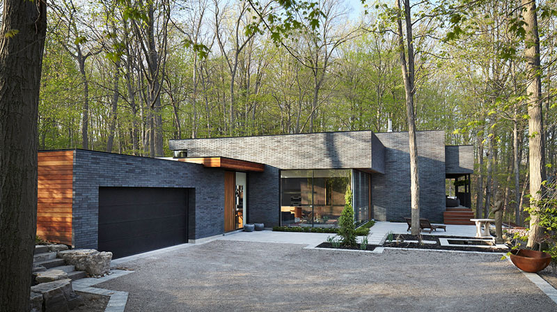 The home’s low, elongated form and earthy materials, like brick and wood, echo the tones of the escarpment and surrounding forest.