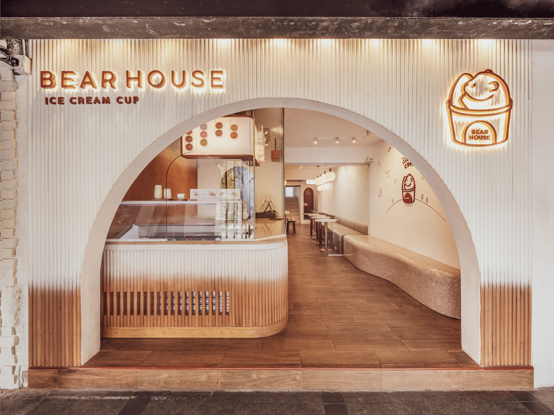 BEARHOUSE blends bubble tea and ice cream in a cozy café inspired by a bear cave and swirling ice cream textures. This small space uses soft two-tone colors and inviting built-in seating to create the perfect hangout.