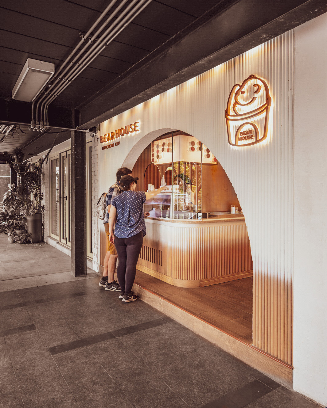 BEARHOUSE blends bubble tea and ice cream in a cozy café inspired by a bear cave and swirling ice cream textures. This small space uses soft two-tone colors and inviting built-in seating to create the perfect hangout.
