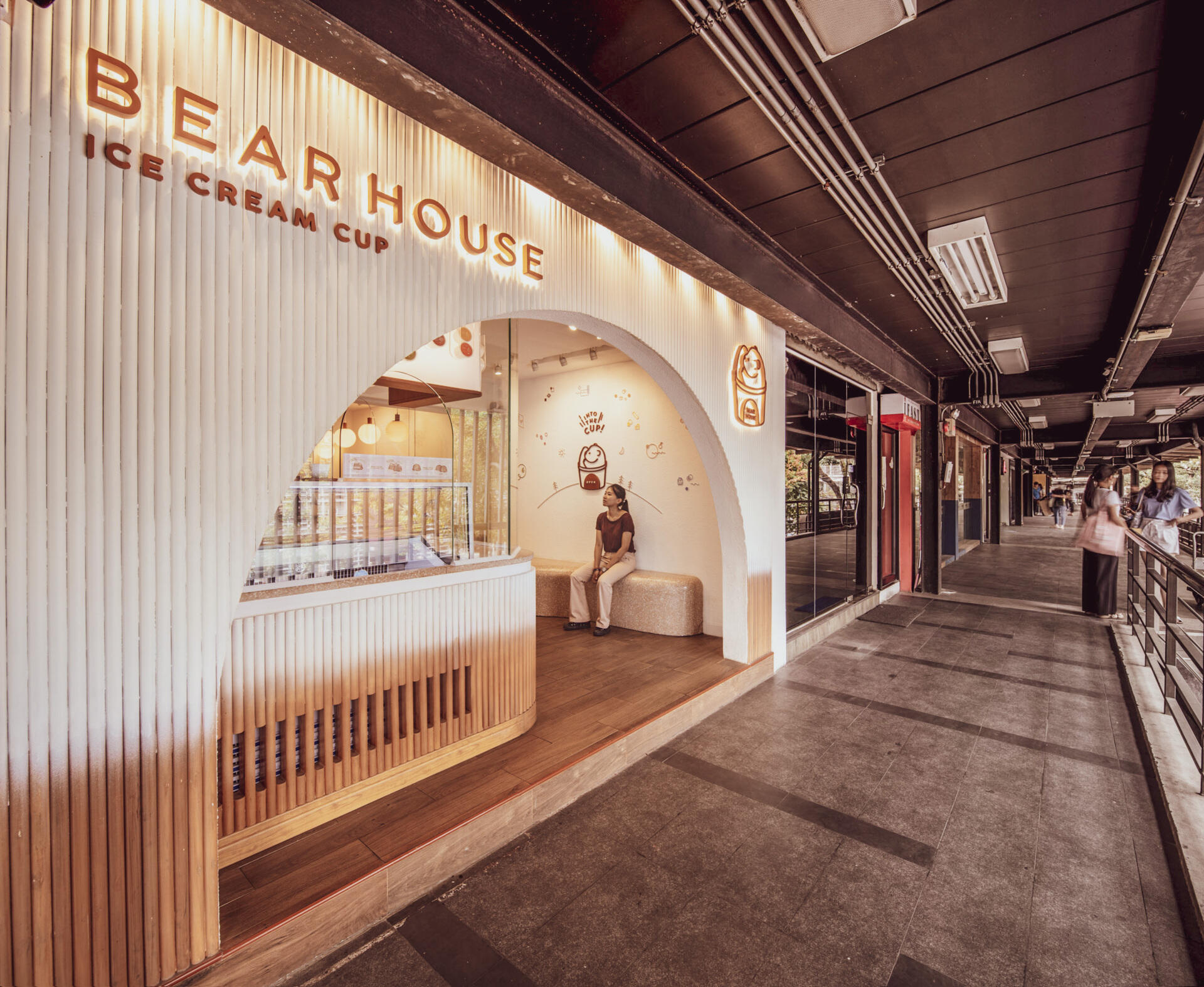 BEARHOUSE blends bubble tea and ice cream in a cozy café inspired by a bear cave and swirling ice cream textures. This small space uses soft two-tone colors and inviting built-in seating to create the perfect hangout.