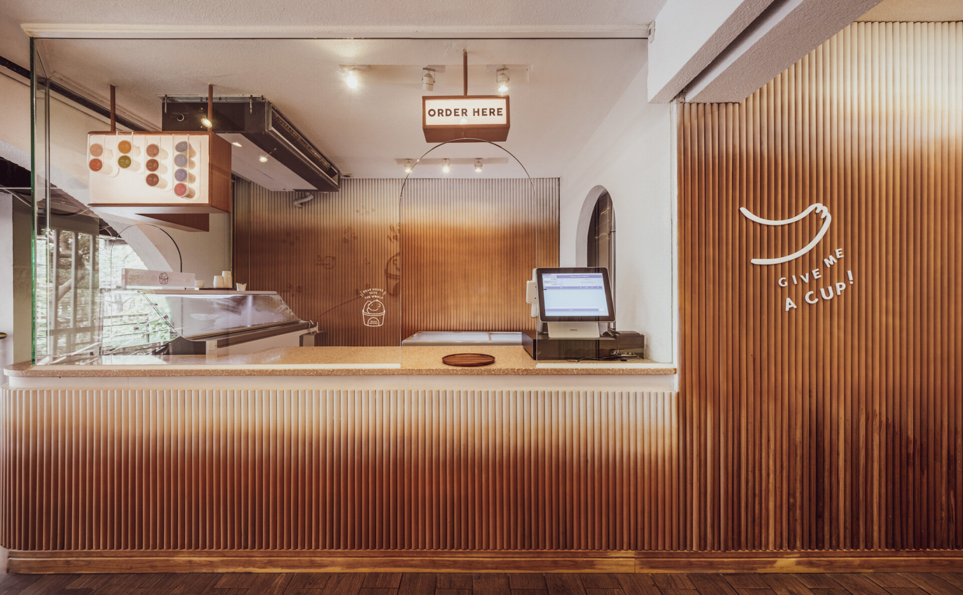 BEARHOUSE blends bubble tea and ice cream in a cozy café inspired by a bear cave and swirling ice cream textures. This small space uses soft two-tone colors and inviting built-in seating to create the perfect hangout.