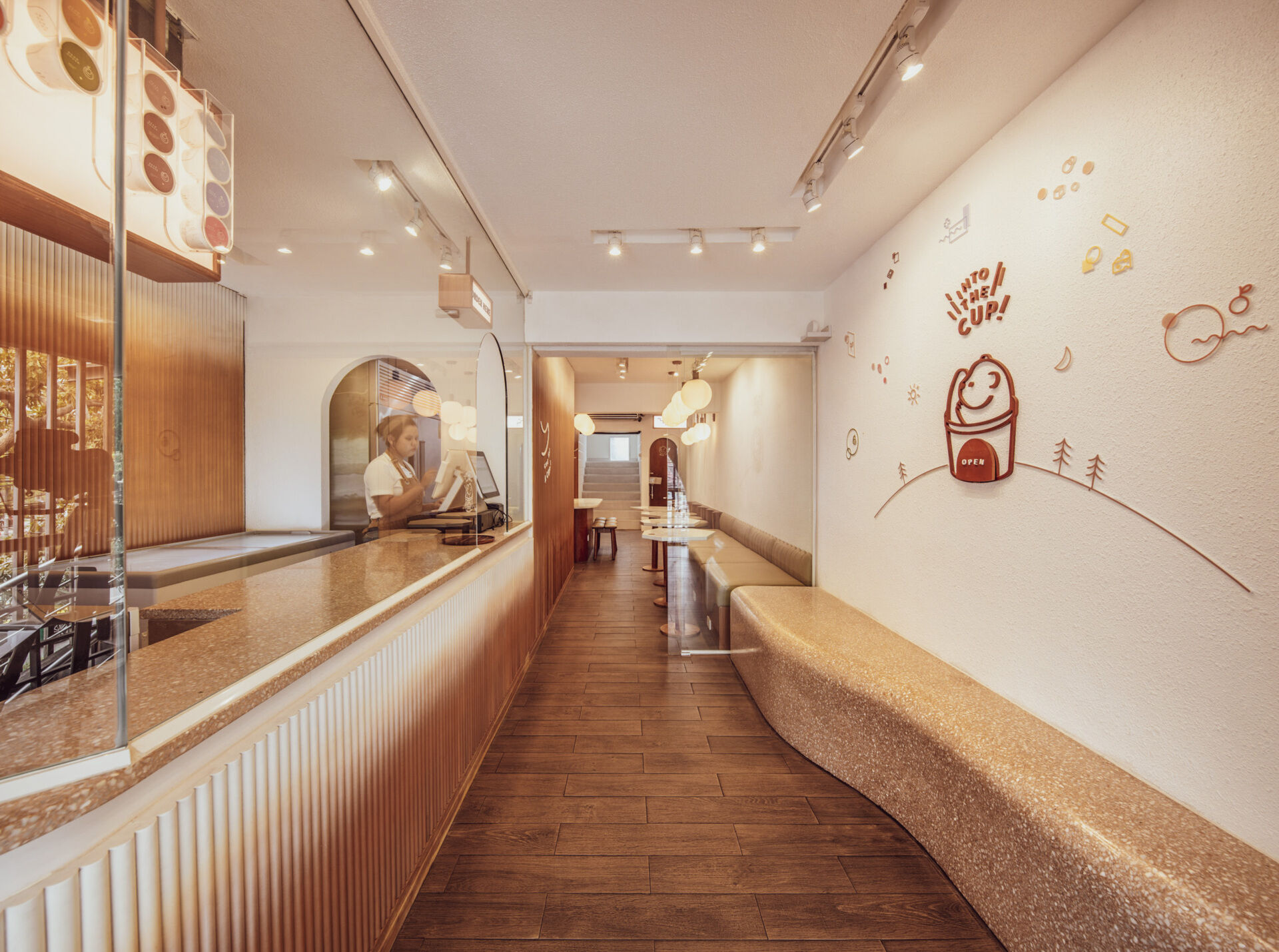 BEARHOUSE blends bubble tea and ice cream in a cozy café inspired by a bear cave and swirling ice cream textures. This small space uses soft two-tone colors and inviting built-in seating to create the perfect hangout.