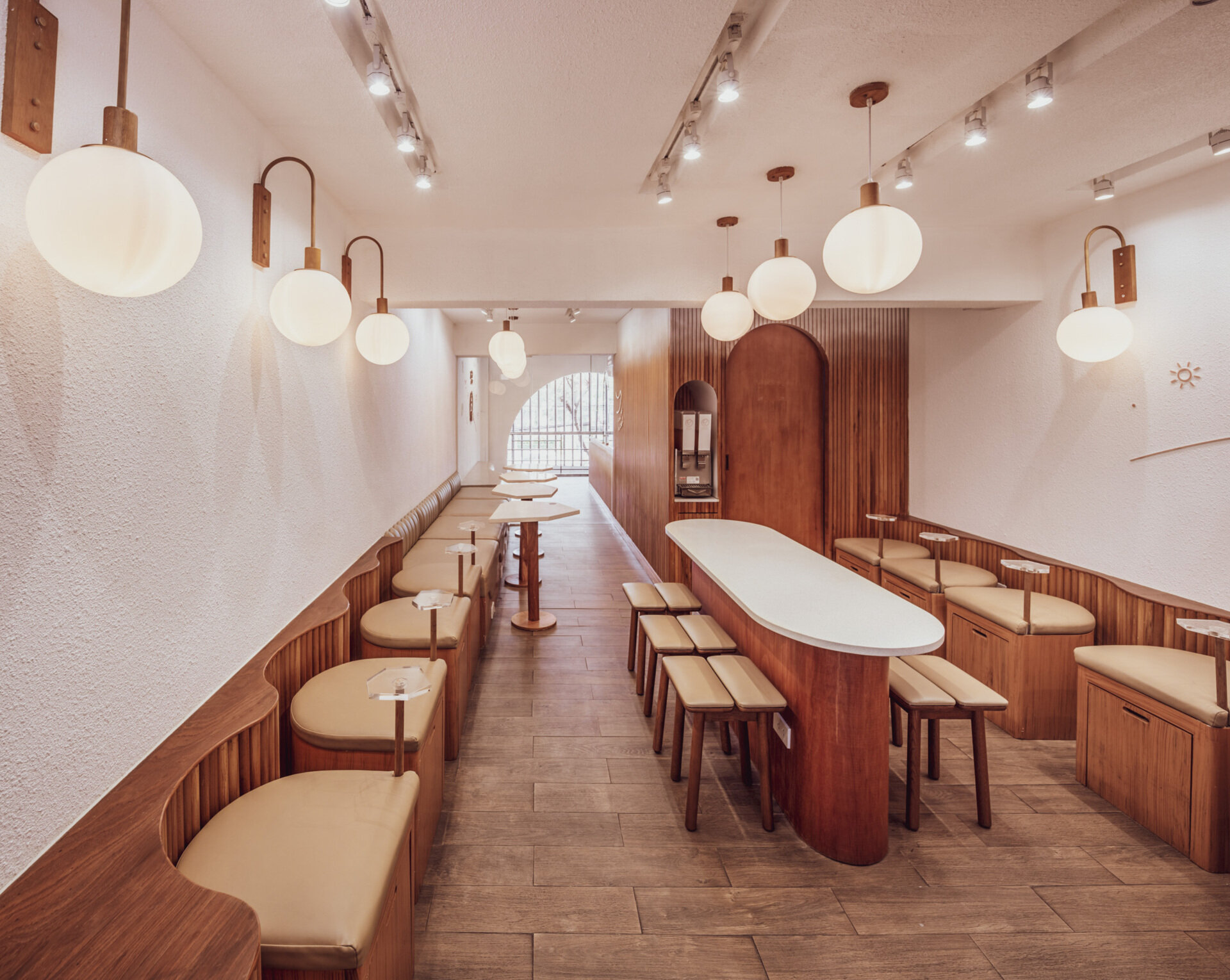 BEARHOUSE blends bubble tea and ice cream in a cozy café inspired by a bear cave and swirling ice cream textures. This small space uses soft two-tone colors and inviting built-in seating to create the perfect hangout.