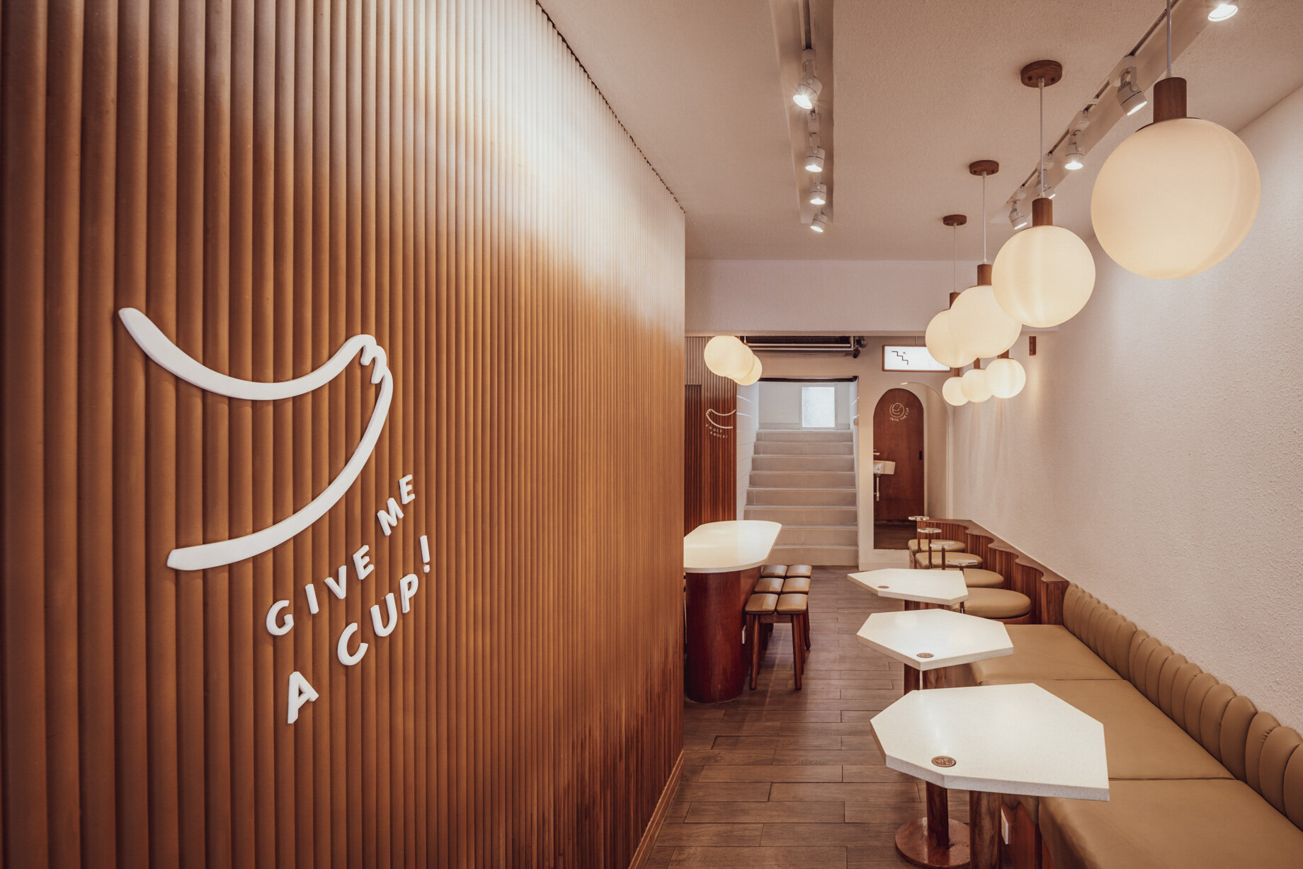 BEARHOUSE blends bubble tea and ice cream in a cozy café inspired by a bear cave and swirling ice cream textures. This small space uses soft two-tone colors and inviting built-in seating to create the perfect hangout.