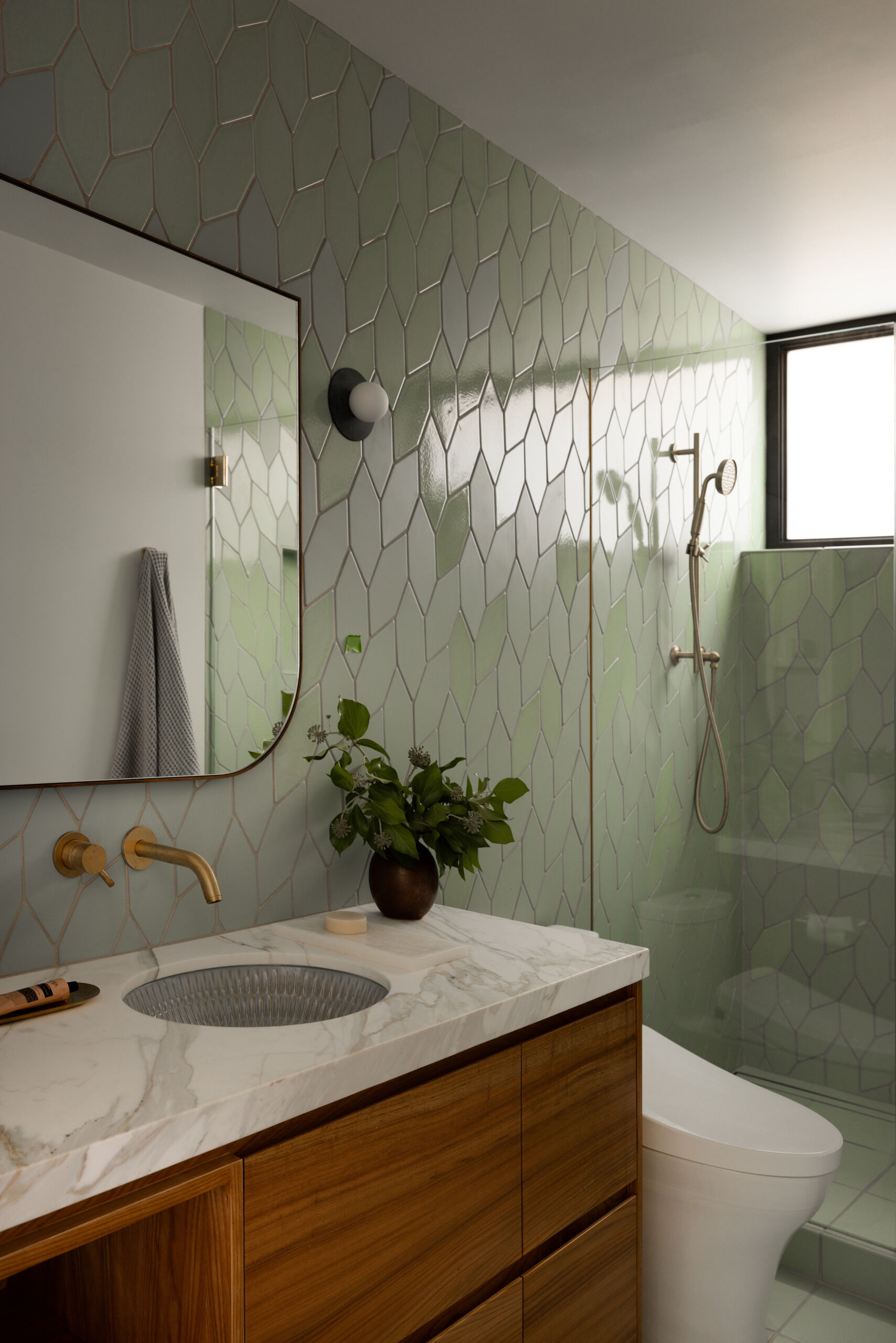 In the kids' bathroom, green geometric tiles turn a utilitarian space into something joyful. It is playful without being overly themed, a smart move for a space that will grow with the kids.