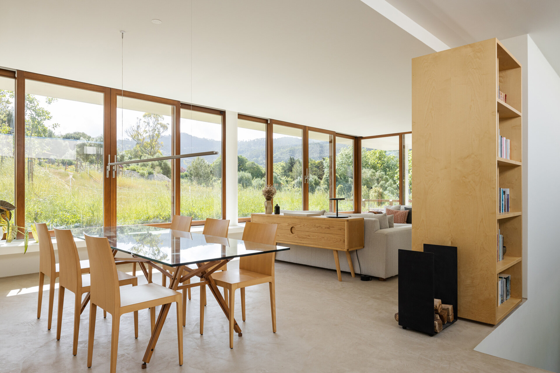 This main living spaces are generous yet serene. Sunlight fills the dining and living space, drawing the landscape into daily life. Warm wood tones add softness, while a glass table keeps the room light and open.