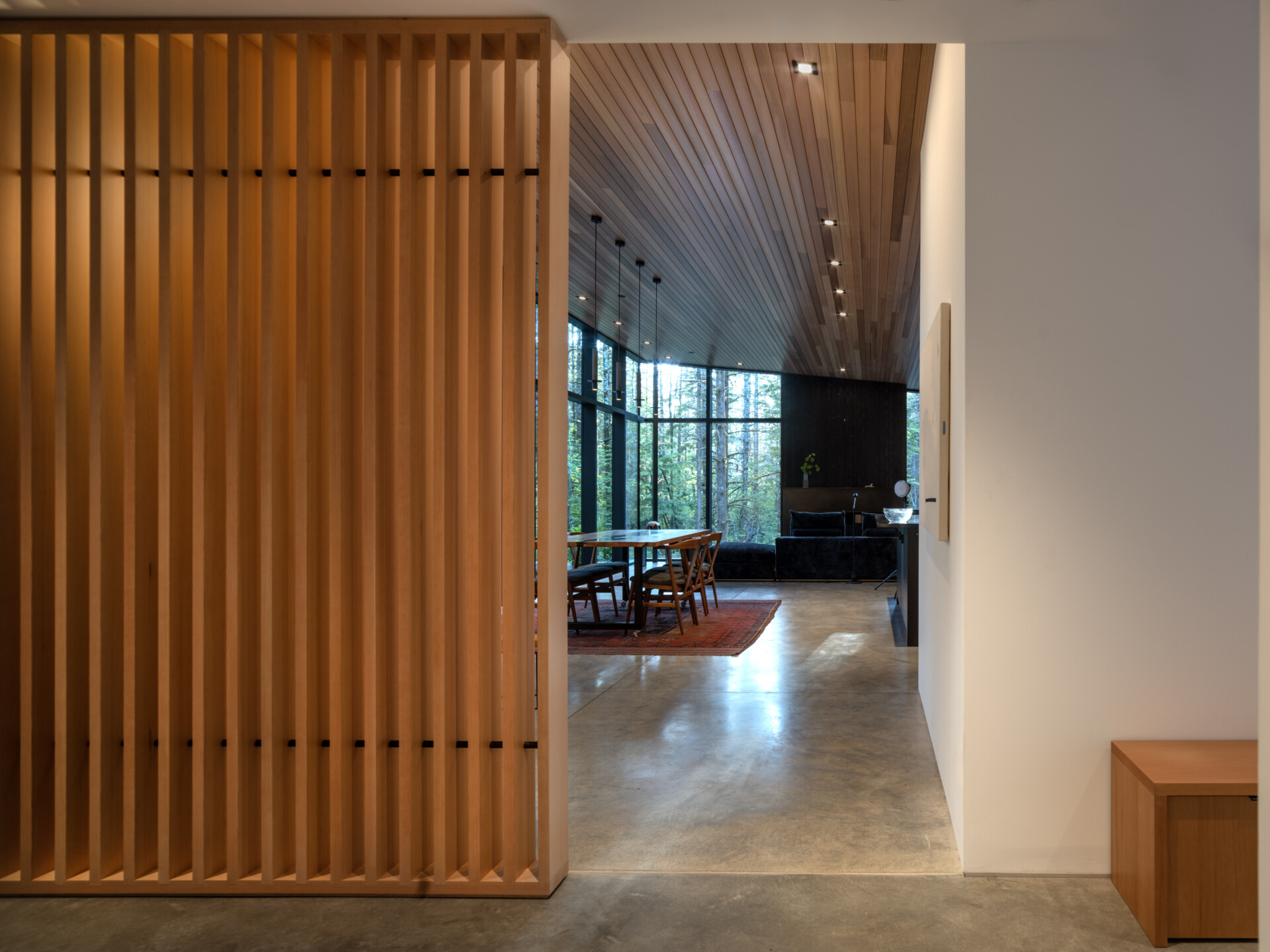 The entry blends natural textures with quiet modernity. A slatted wood screen adds privacy and rhythm, while stone and raw wood accents ground the space.