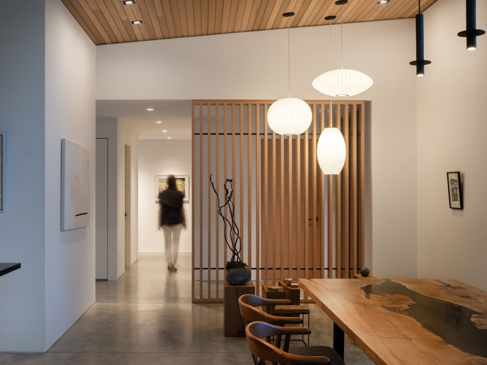 The entry blends natural textures with quiet modernity. A slatted wood screen adds privacy and rhythm, while stone and raw wood accents ground the space.