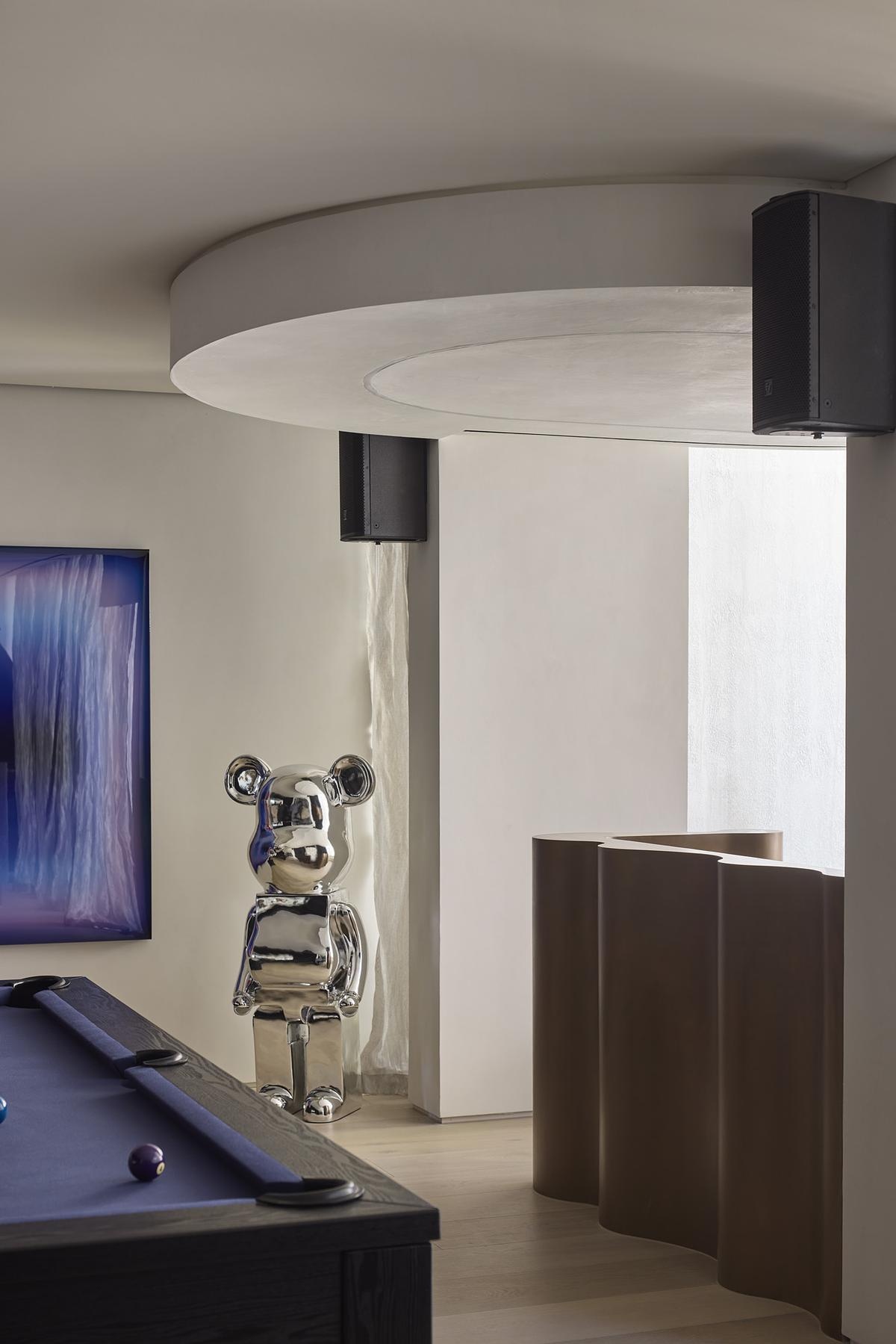 The entertainment zone of a modern home includes a DJ booth and opens onto a private courtyard, balancing boldness and ease. A cocktail bar accented with bronze and brass speaks to the home's quiet sense of glamour.