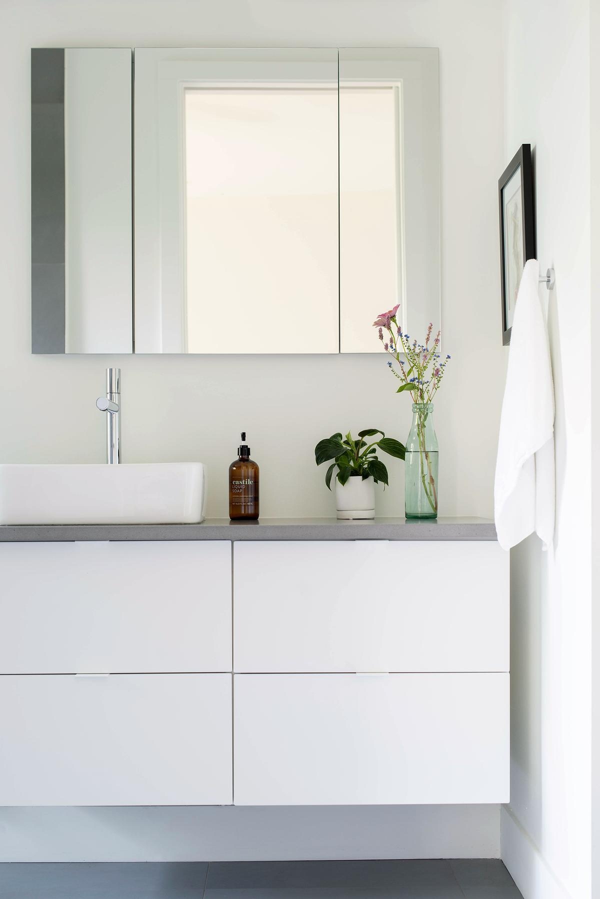 This primary ensuite bathroom keeps things simple and clean, featuring a white vanity topped with a grey countertop. A freestanding bathtub shares the space with the shower, blending functionality and understated style.