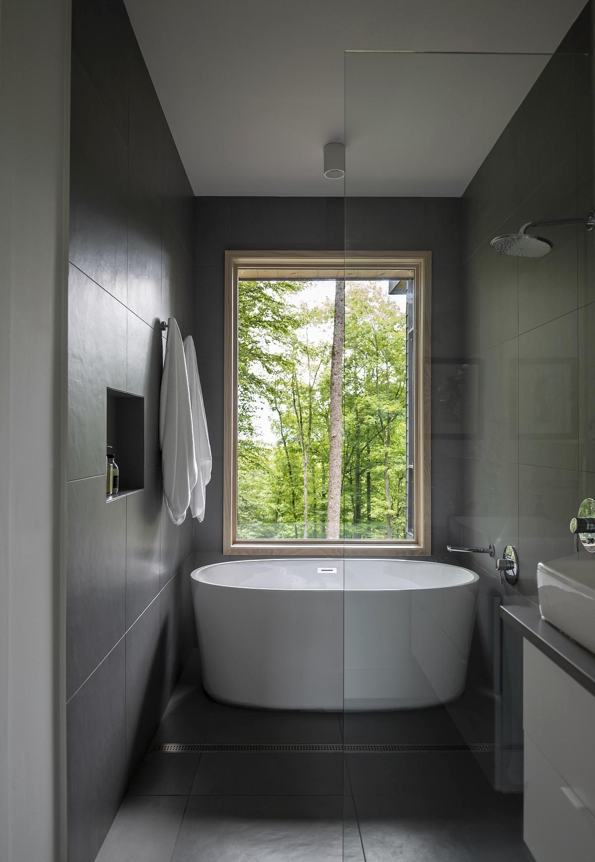 This primary ensuite bathroom keeps things simple and clean, featuring a white vanity topped with a grey countertop. A freestanding bathtub shares the space with the shower, blending functionality and understated style.