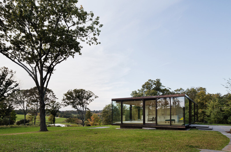 A striking glass guest house with a slatted wood core, cantilevered roof, and high-performance triple-pane glazing, designed to sit lightly on the land.