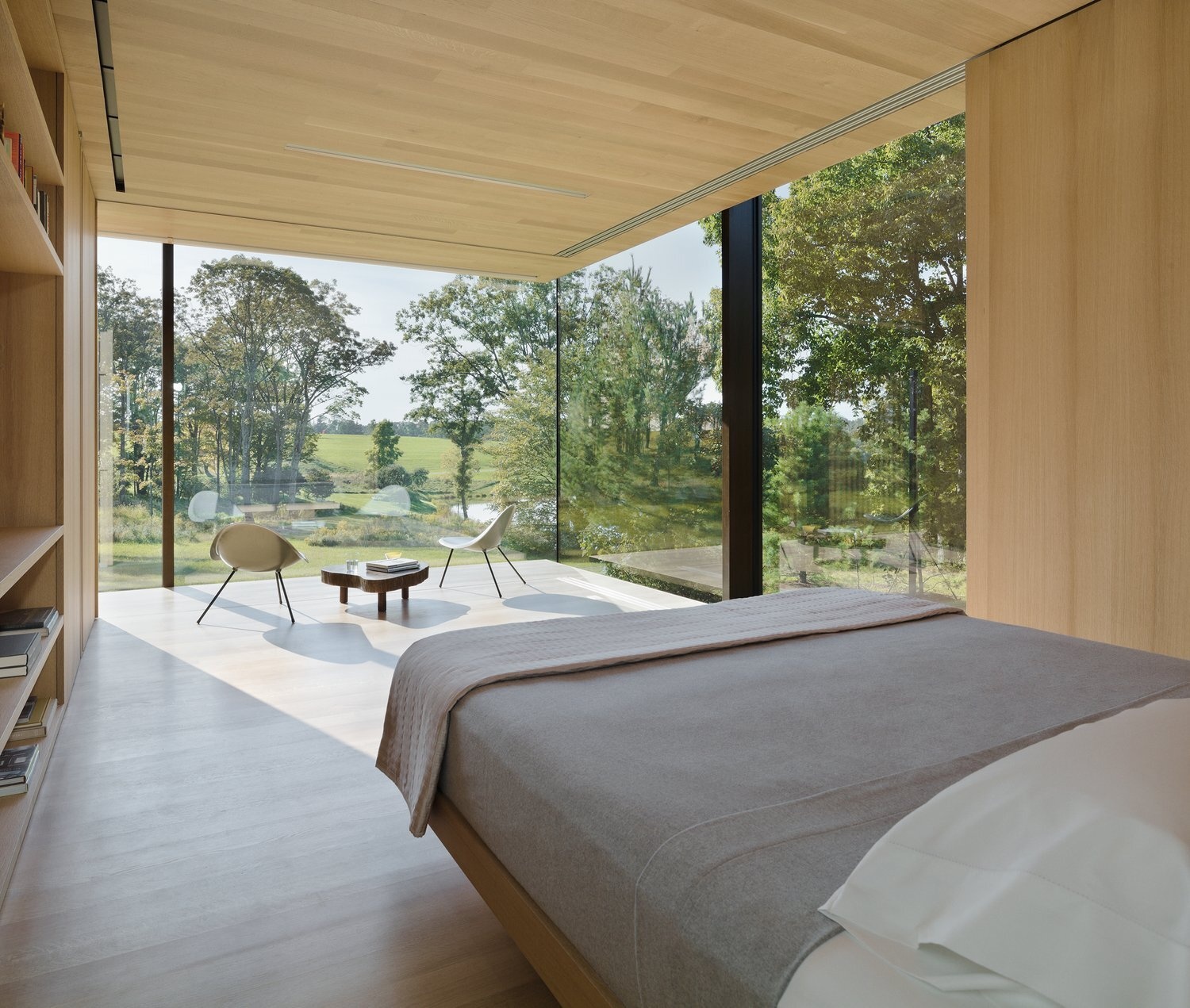 The main bedroom in this modern guest house opens to sweeping views and features sliding wood panels that offer privacy and light control with ease.