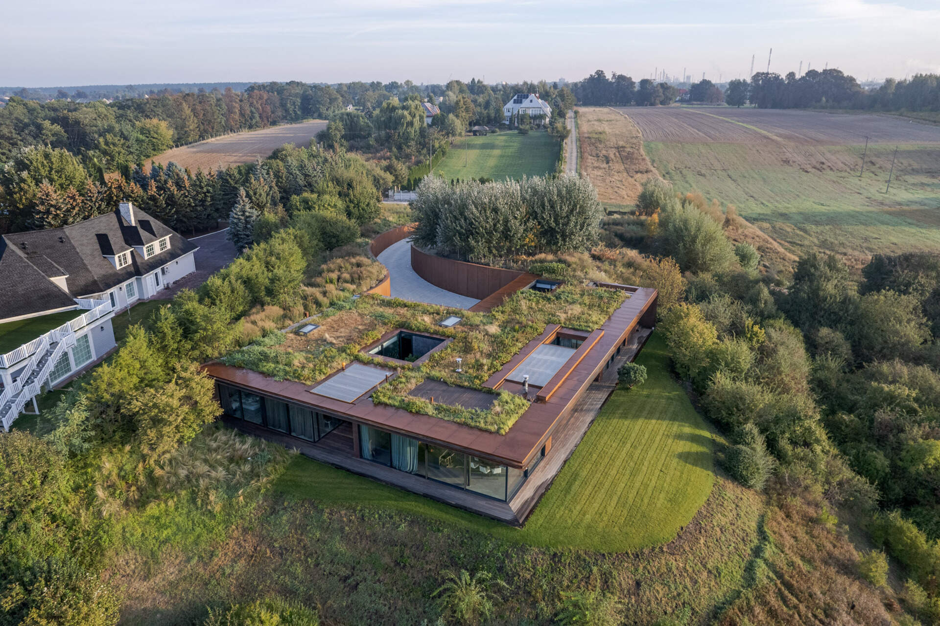 This modern home vanishes into the hillside with a green roof, corten steel facade, and panoramic river views.