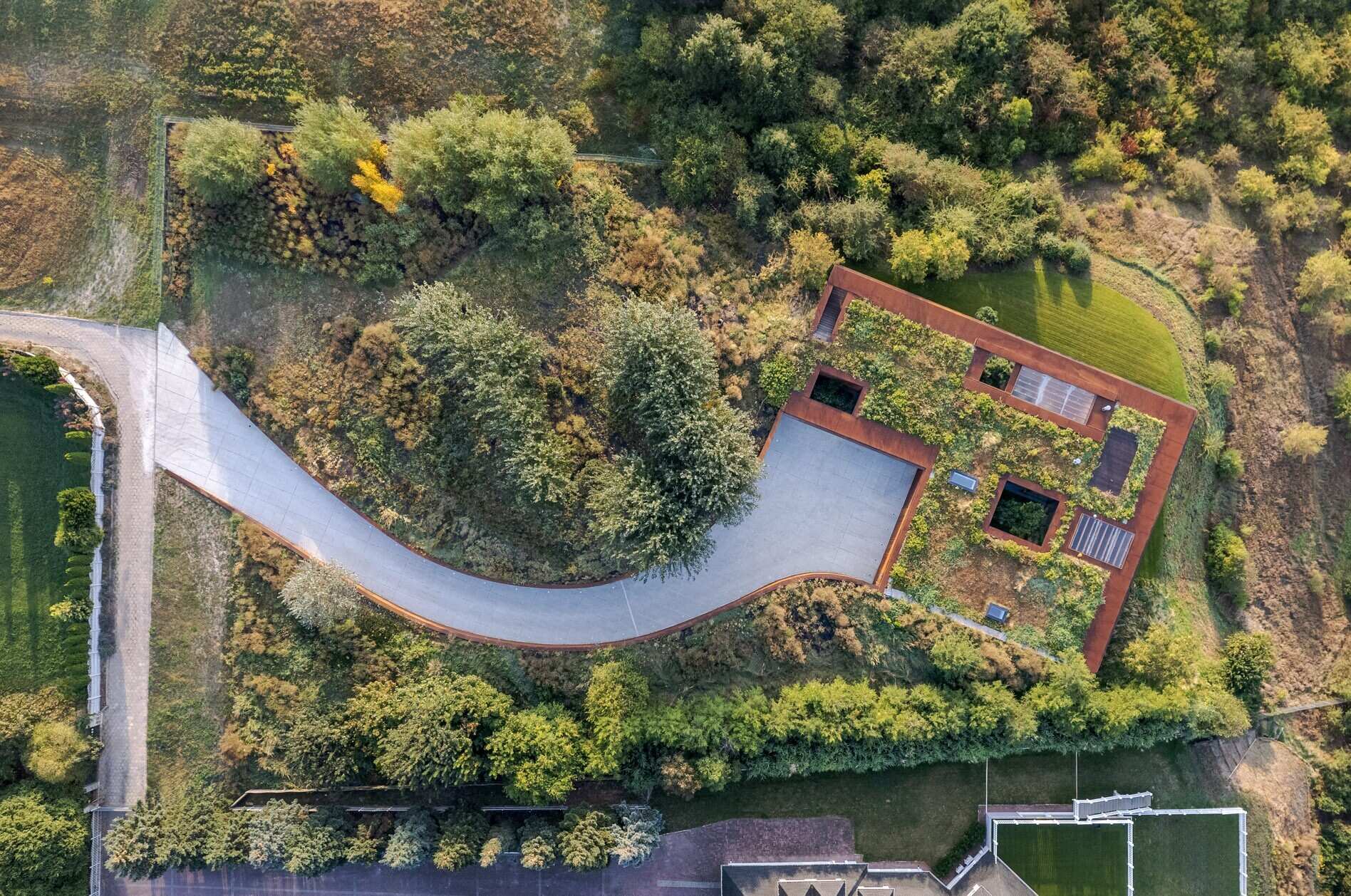 This modern home vanishes into the hillside with a green roof, corten steel facade, and panoramic river views.
