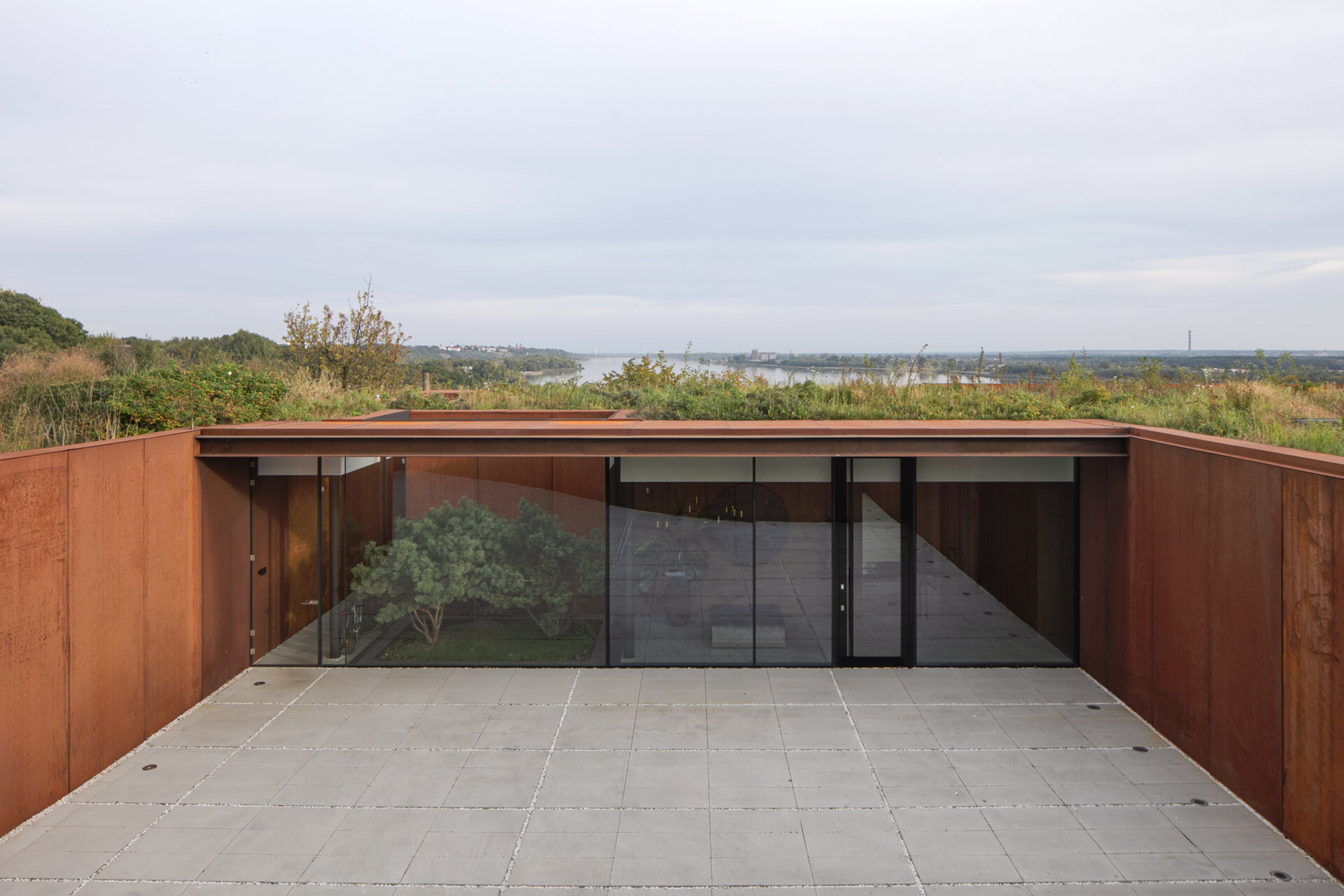 To avoid disrupting the natural meadow above, the entire home is covered by a planted green roof using species native to the riverbank.