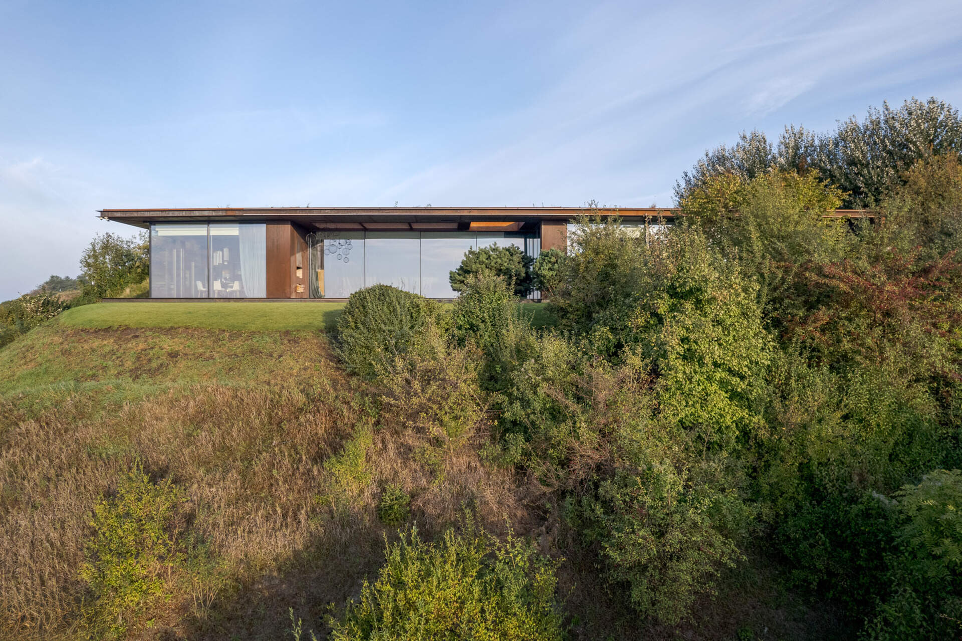 Large openings frame specific views of the river, slope, and vegetation. The 12-meter-wide sliding door in the living area allows the entire southeast wall to open up to the outdoors.