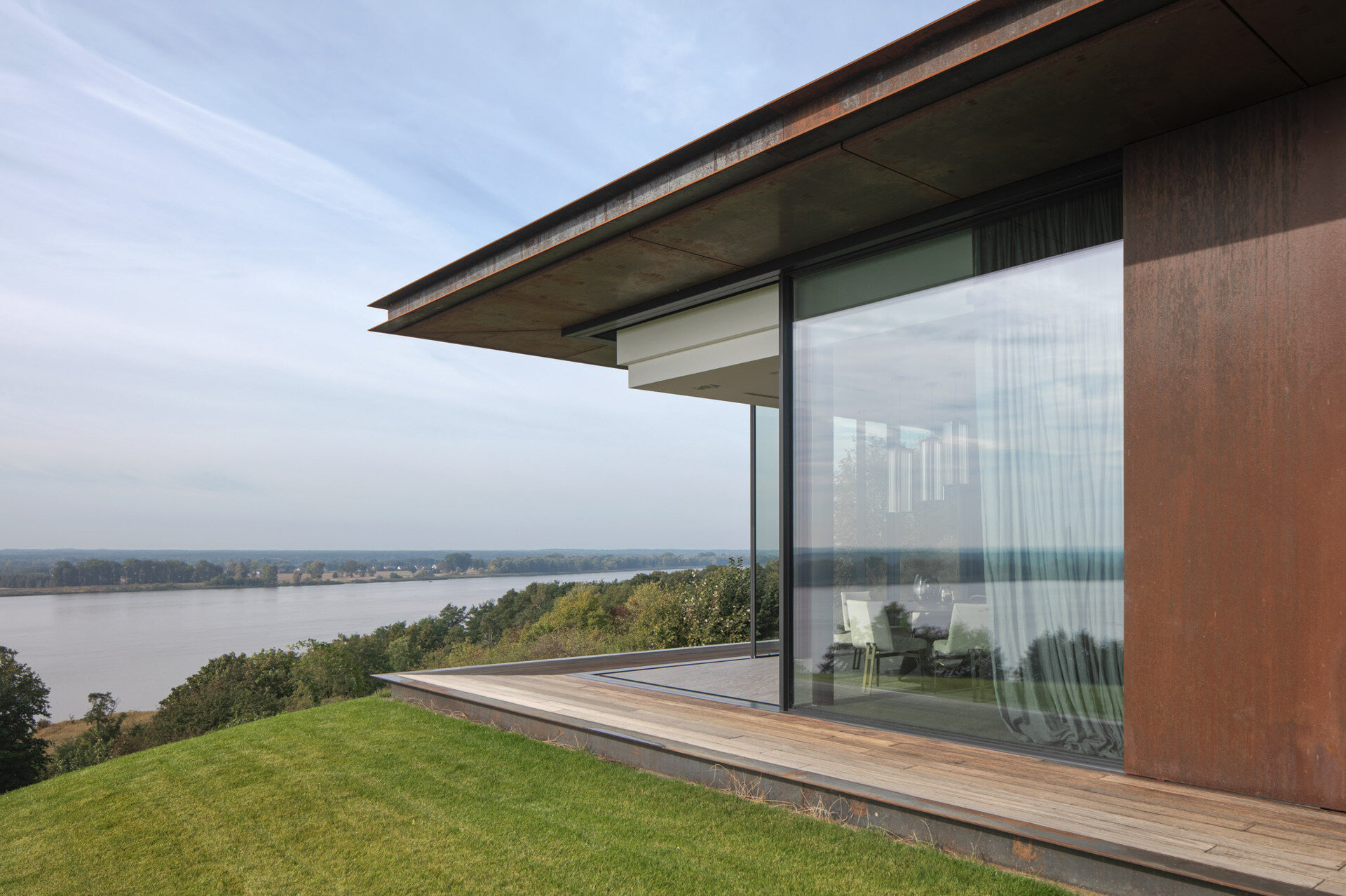Large openings frame specific views of the river, slope, and vegetation. The 12-meter-wide sliding door in the living area allows the entire southeast wall to open up to the outdoors.