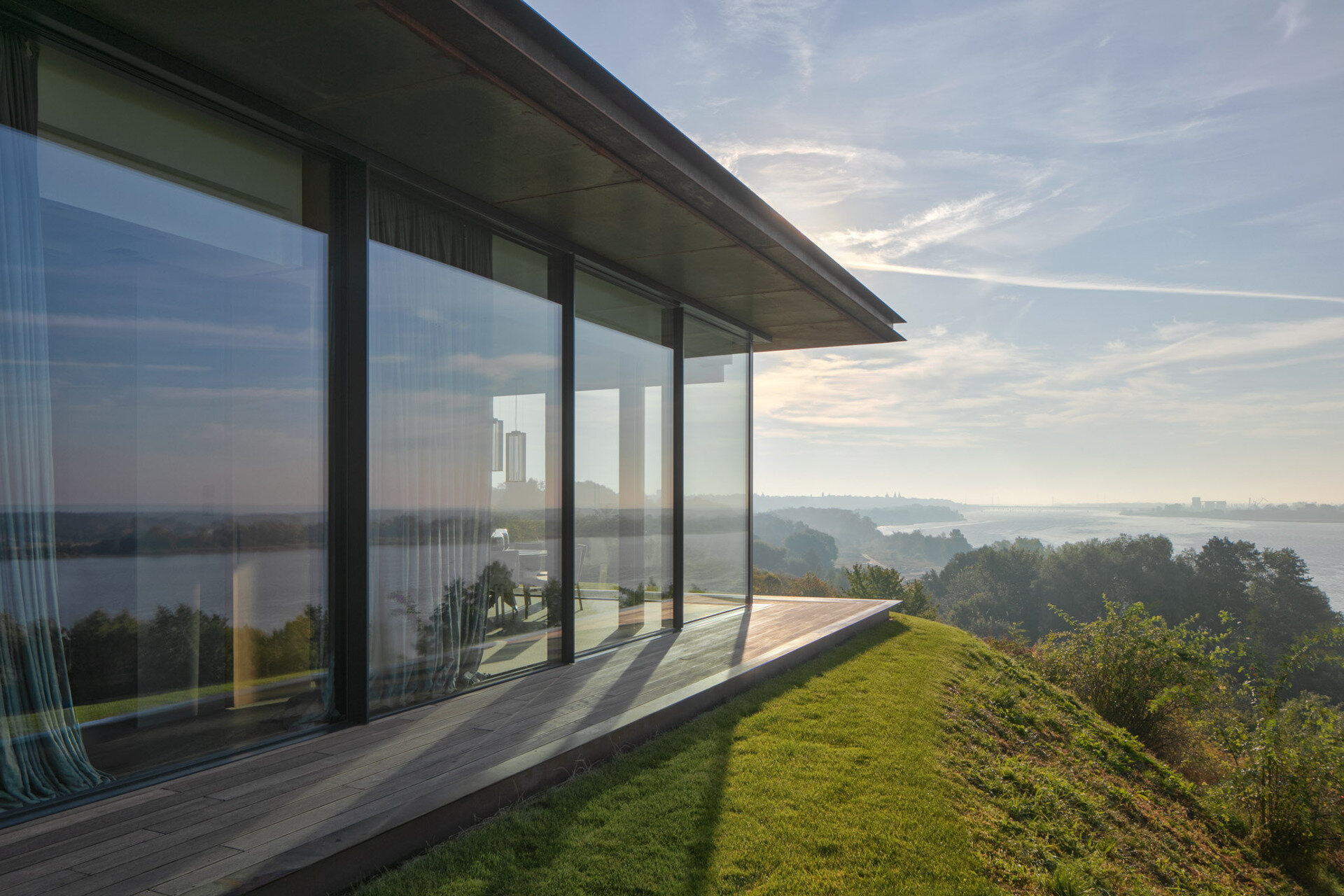 Large openings frame specific views of the river, slope, and vegetation. The 12-meter-wide sliding door in the living area allows the entire southeast wall to open up to the outdoors.