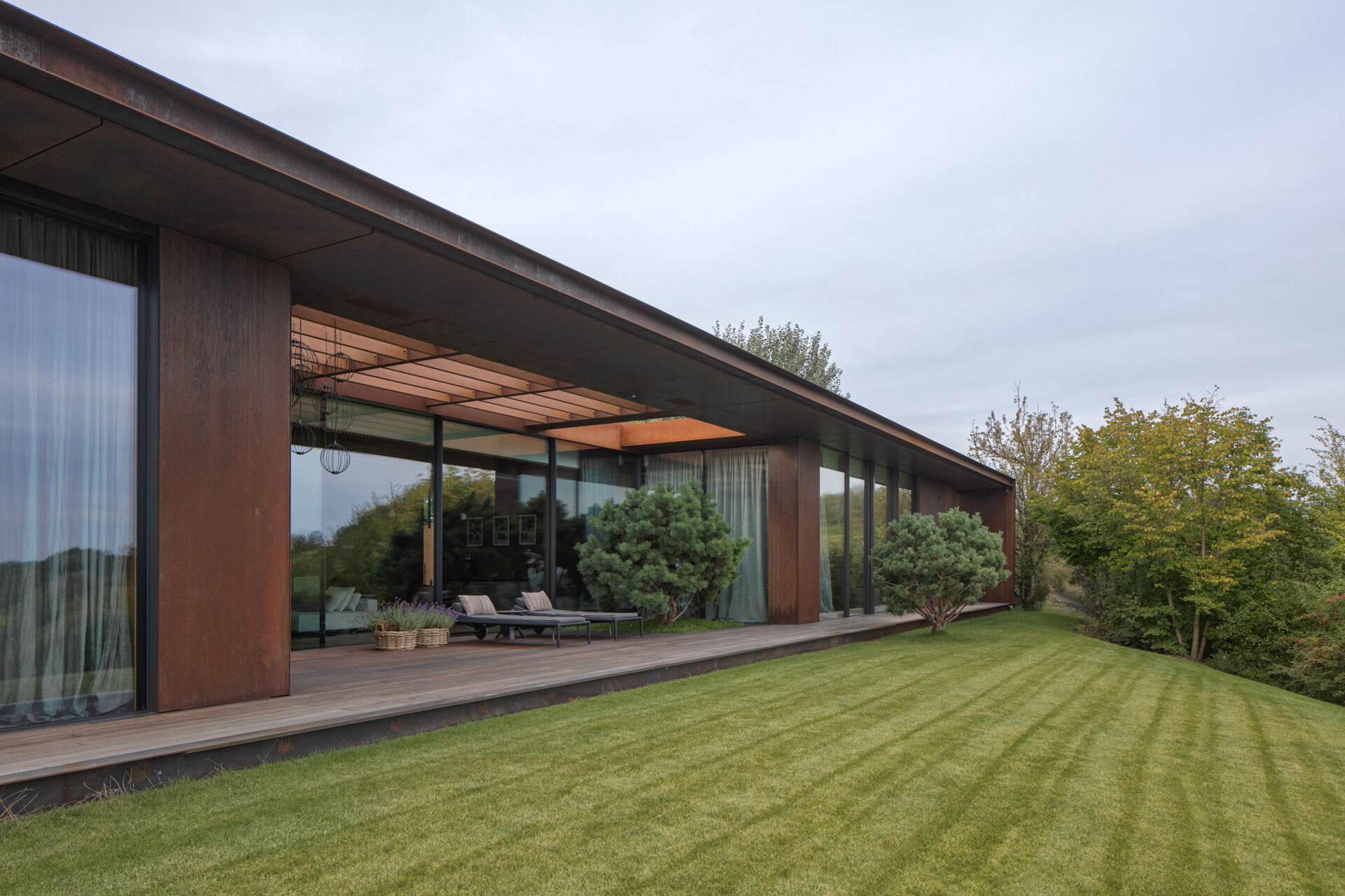 This modern home terrace extends directly from the main living space and faces the river. It's positioned for sunlight and views without elevation, continuing the natural incline of the site. It acts as a threshold between interior and landscape, not a platform above it, but a surface within it.