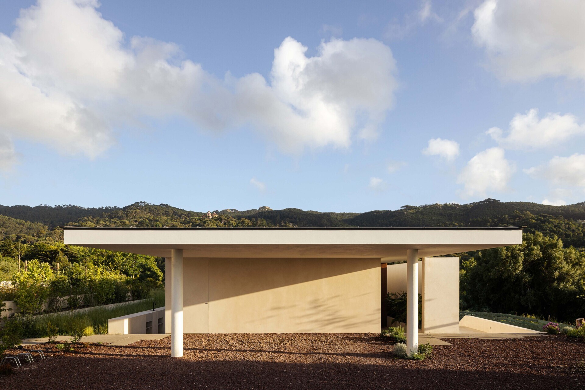 This hillside home uses the natural slope to its advantage. Half-buried and minimal in form, it blends seamlessly with its environment. The green roof disappears into the landscape, helping regulate temperature while softening the structure’s visual impact.