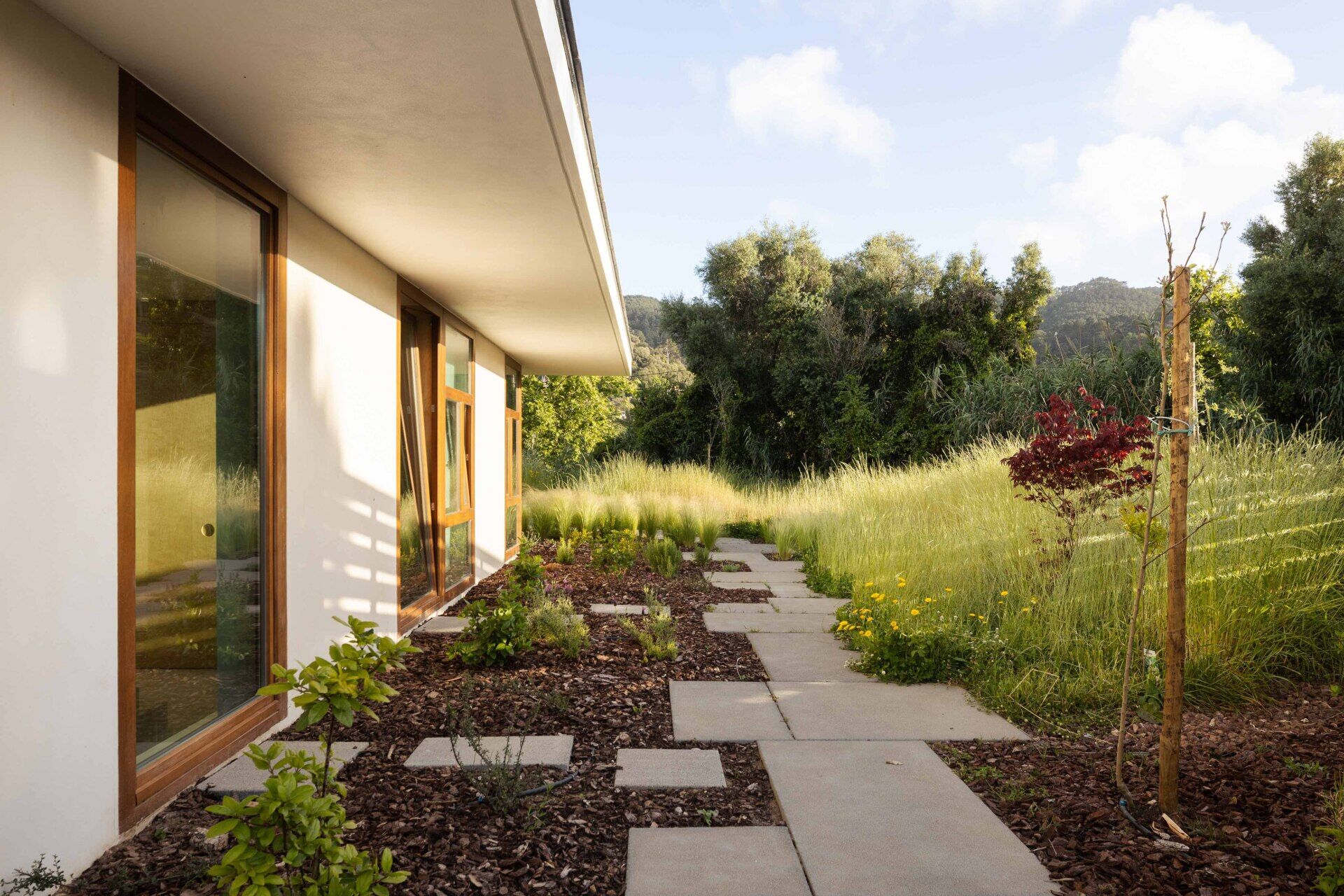 This hillside home uses the natural slope to its advantage. Half-buried and minimal in form, it blends seamlessly with its environment. The green roof disappears into the landscape, helping regulate temperature while softening the structure’s visual impact.