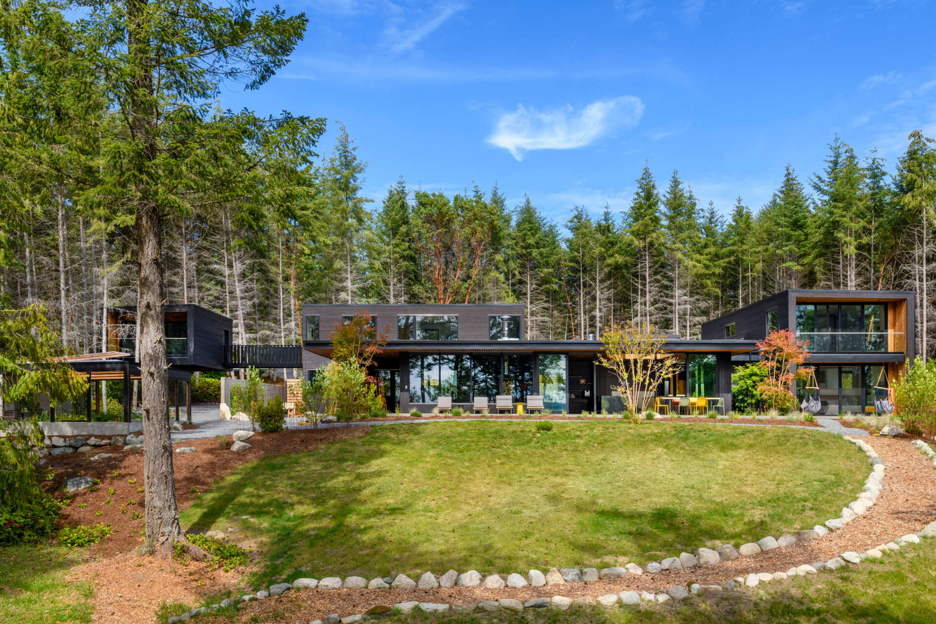 A stepped, low-profile home clad in charred yakisugi siding, designed to blend into the hillside and forest.