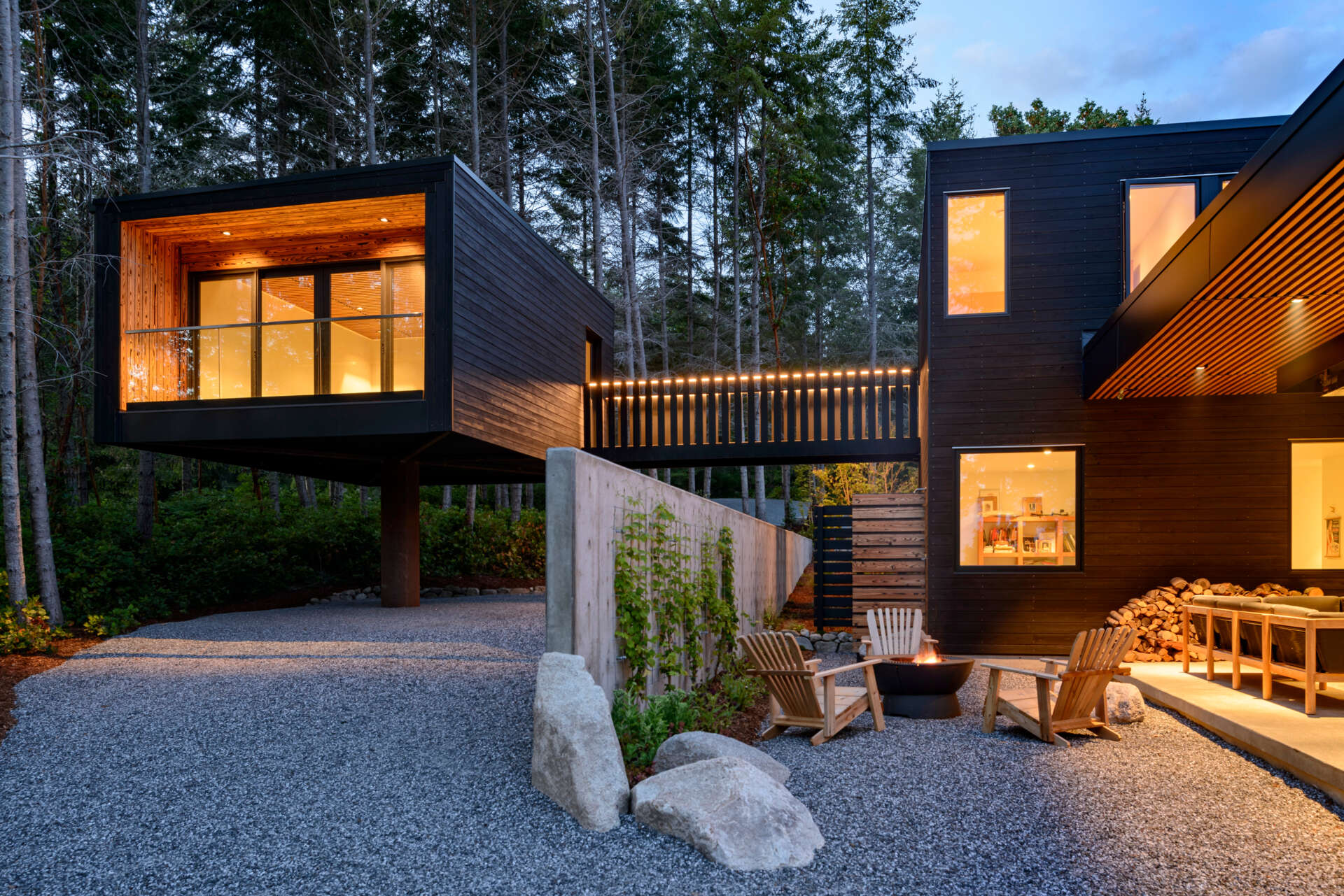 A stepped, low-profile home clad in charred yakisugi siding, designed to blend into the hillside and forest.