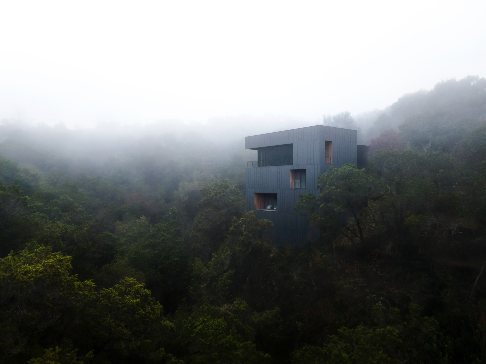 The exterior of this modern home is wrapped in vertical steel panels designed to weather, while deep wood-lined recesses frame curated views and allow light to shift throughout the day.