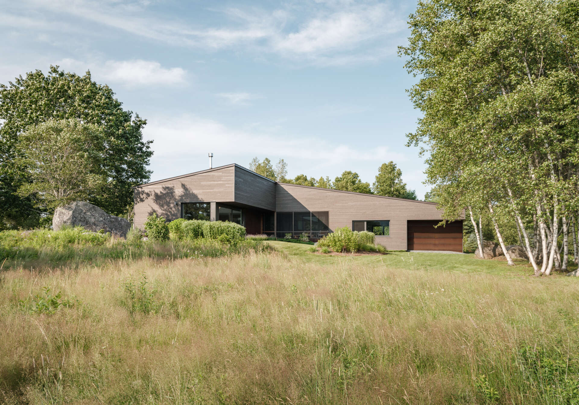 This Maine home unites workshop, garage, and living spaces under one simple gabled roof, with smart transitions and passive solar design woven into every detail.