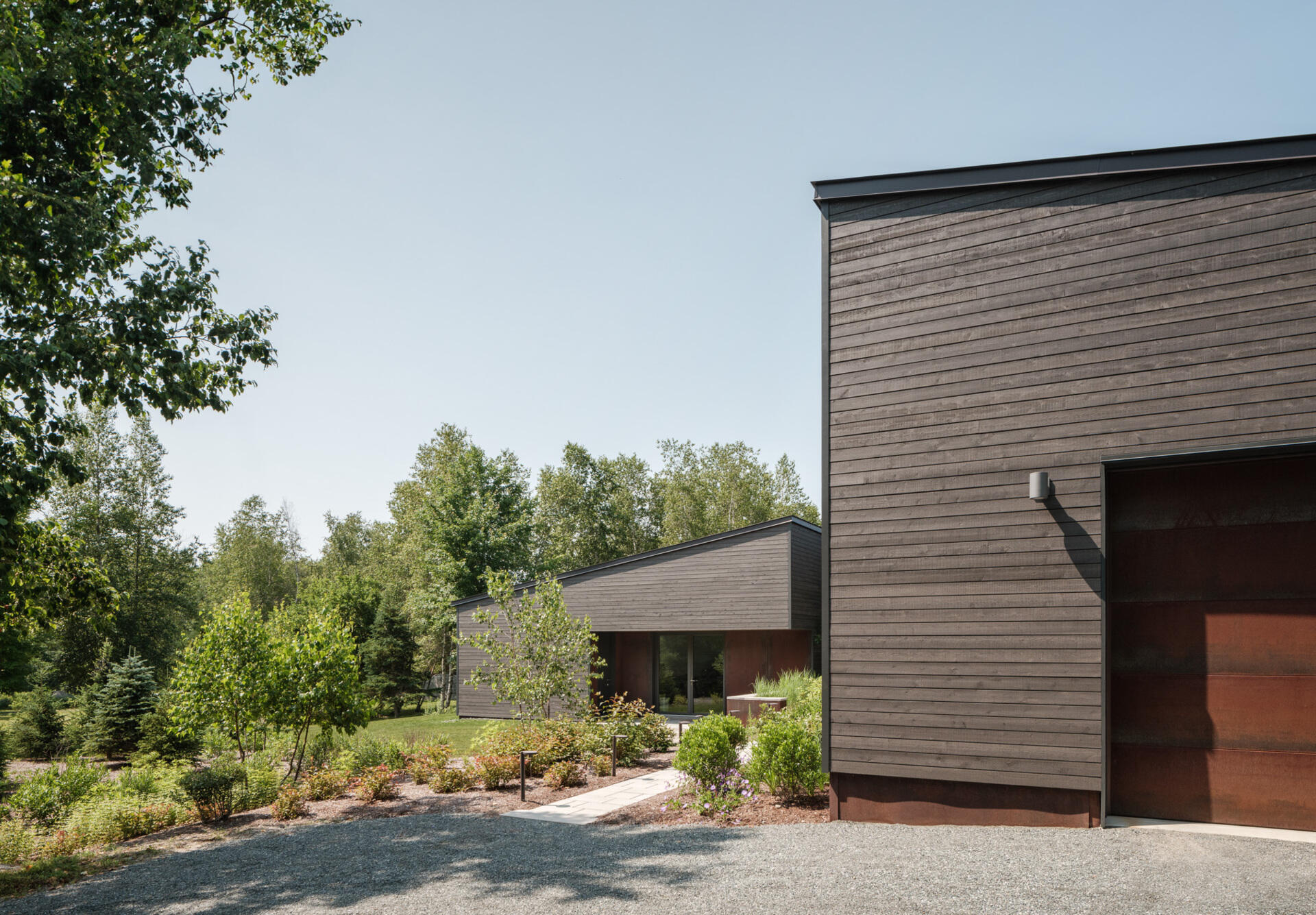 Stained cedar siding and Corten steel panels give this house a modern, grounded look that blends beautifully with the wooded riverside landscape.