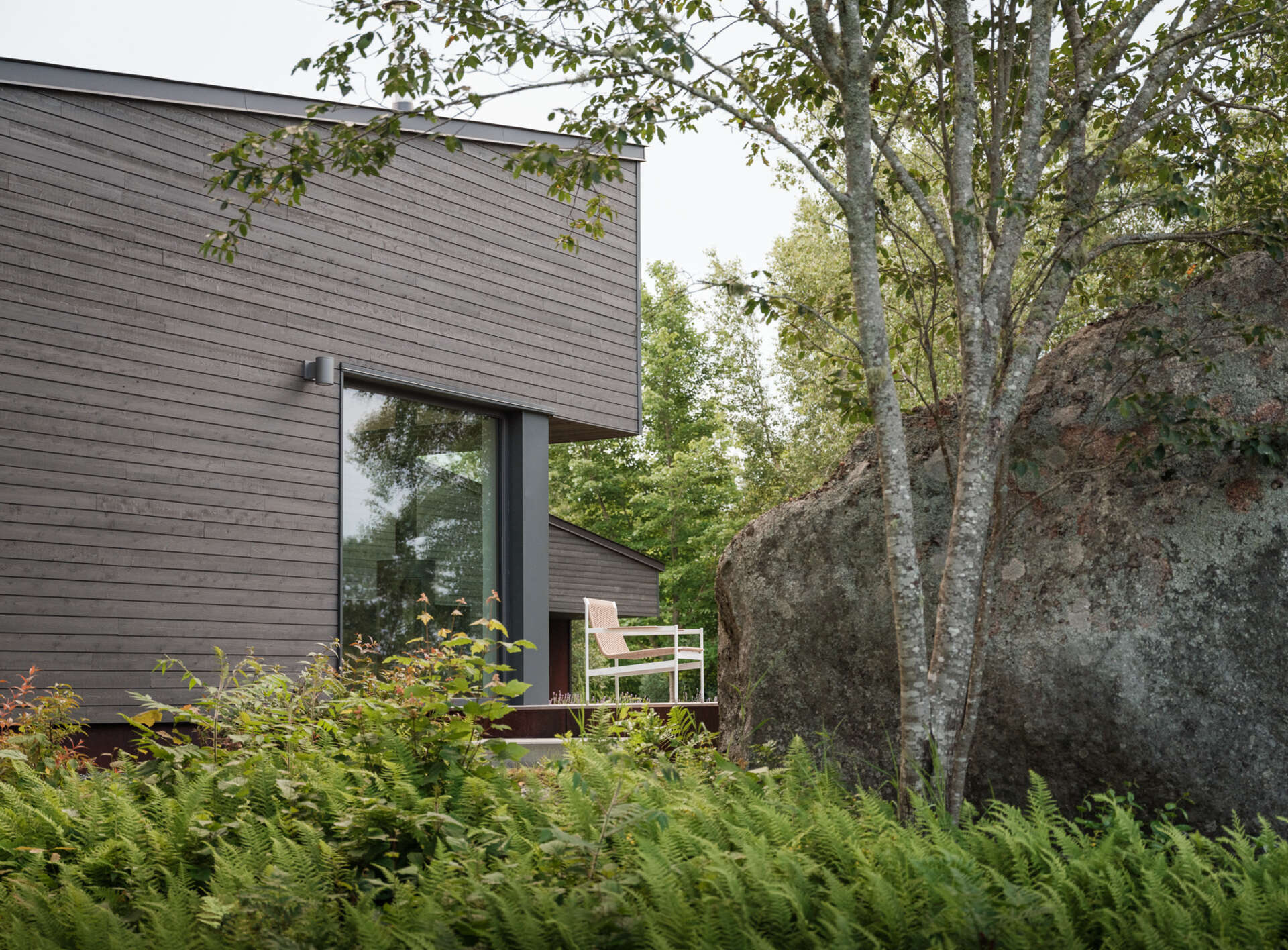 Stained cedar siding and Corten steel panels give this house a modern, grounded look that blends beautifully with the wooded riverside landscape.