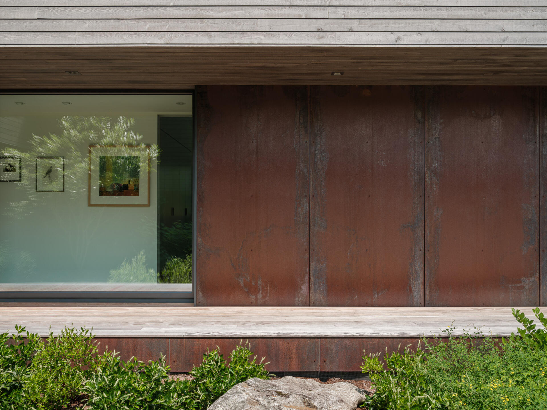 Stained cedar siding and Corten steel panels give this house a modern, grounded look that blends beautifully with the wooded riverside landscape.