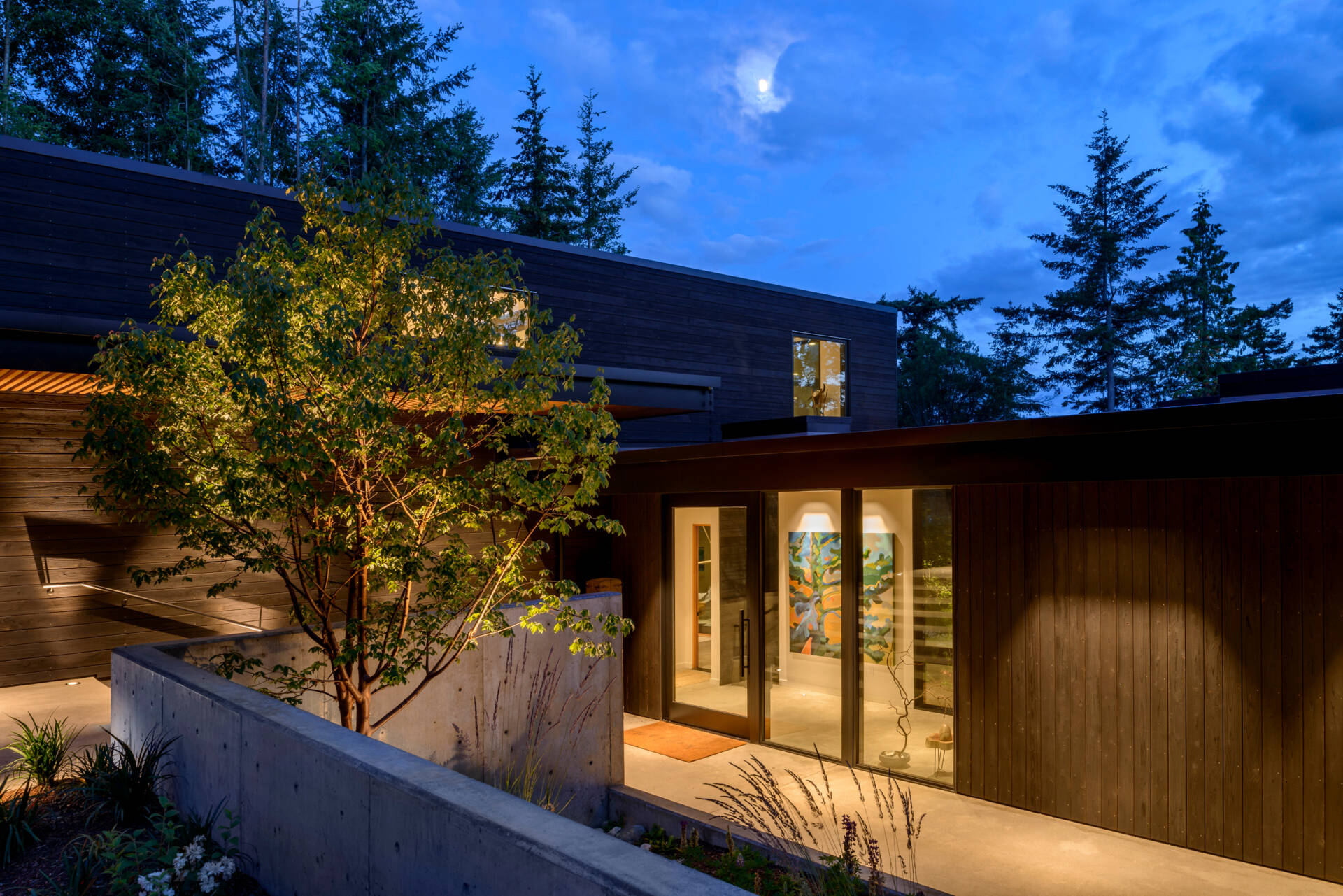 The home is accessible from both a driveway and a footpath, reflecting the dual modes of arrival common to the island. The entry sequence is subtle, with minimal hardscape and native landscaping that blends into the forested site.