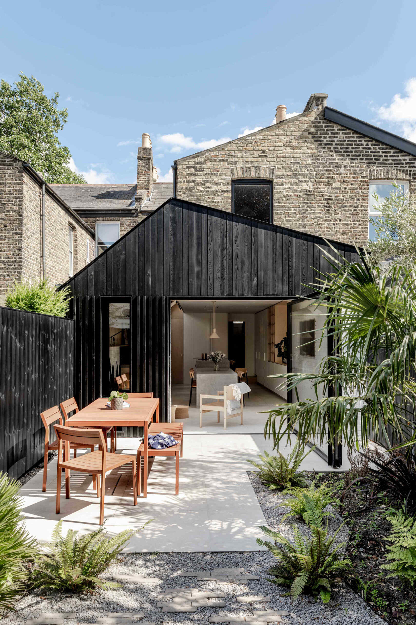 Clad in blackened cedar and filled with light, the new extension opens to the garden and unites kitchen, dining, and living into one calm space.